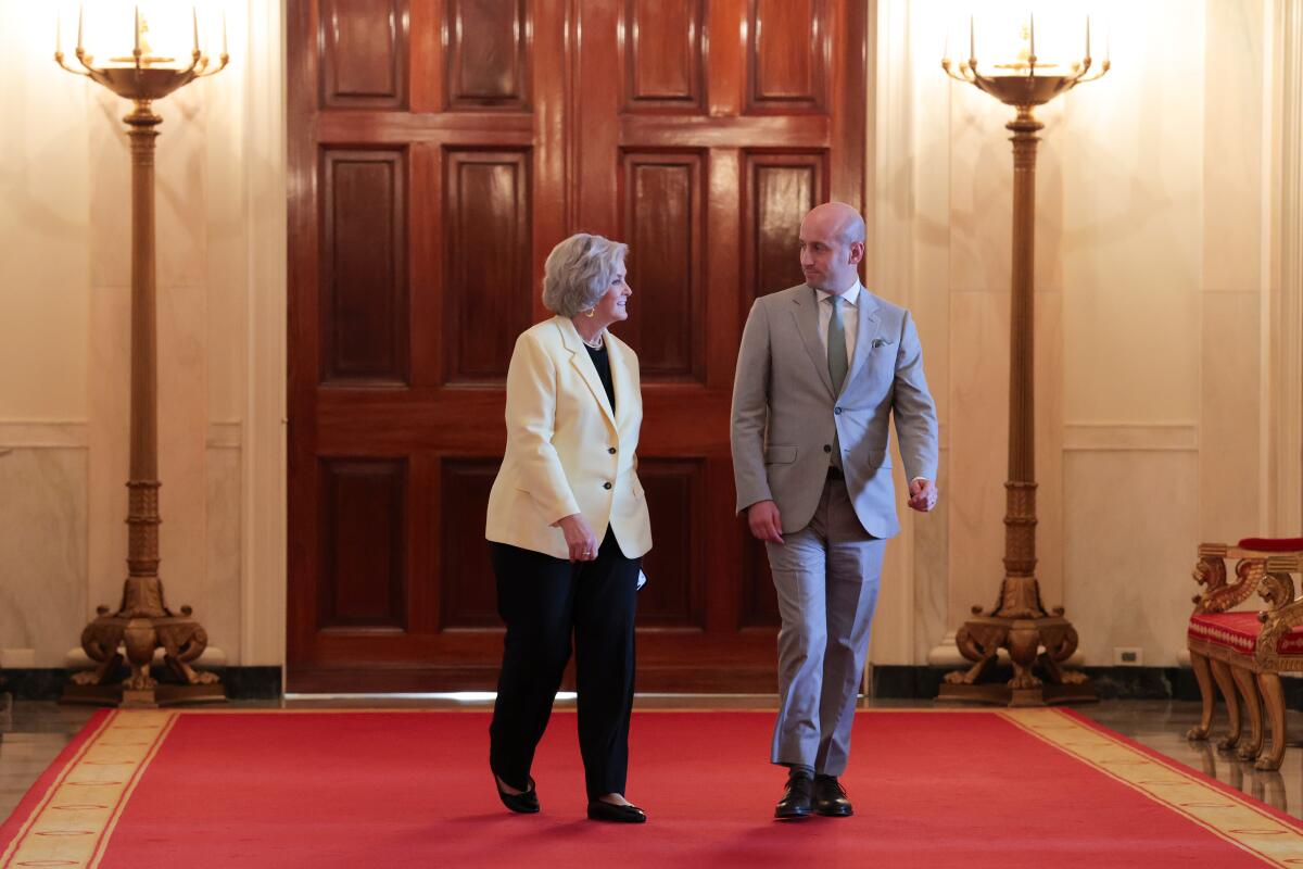 A man and a woman walk down a red carpet in a building