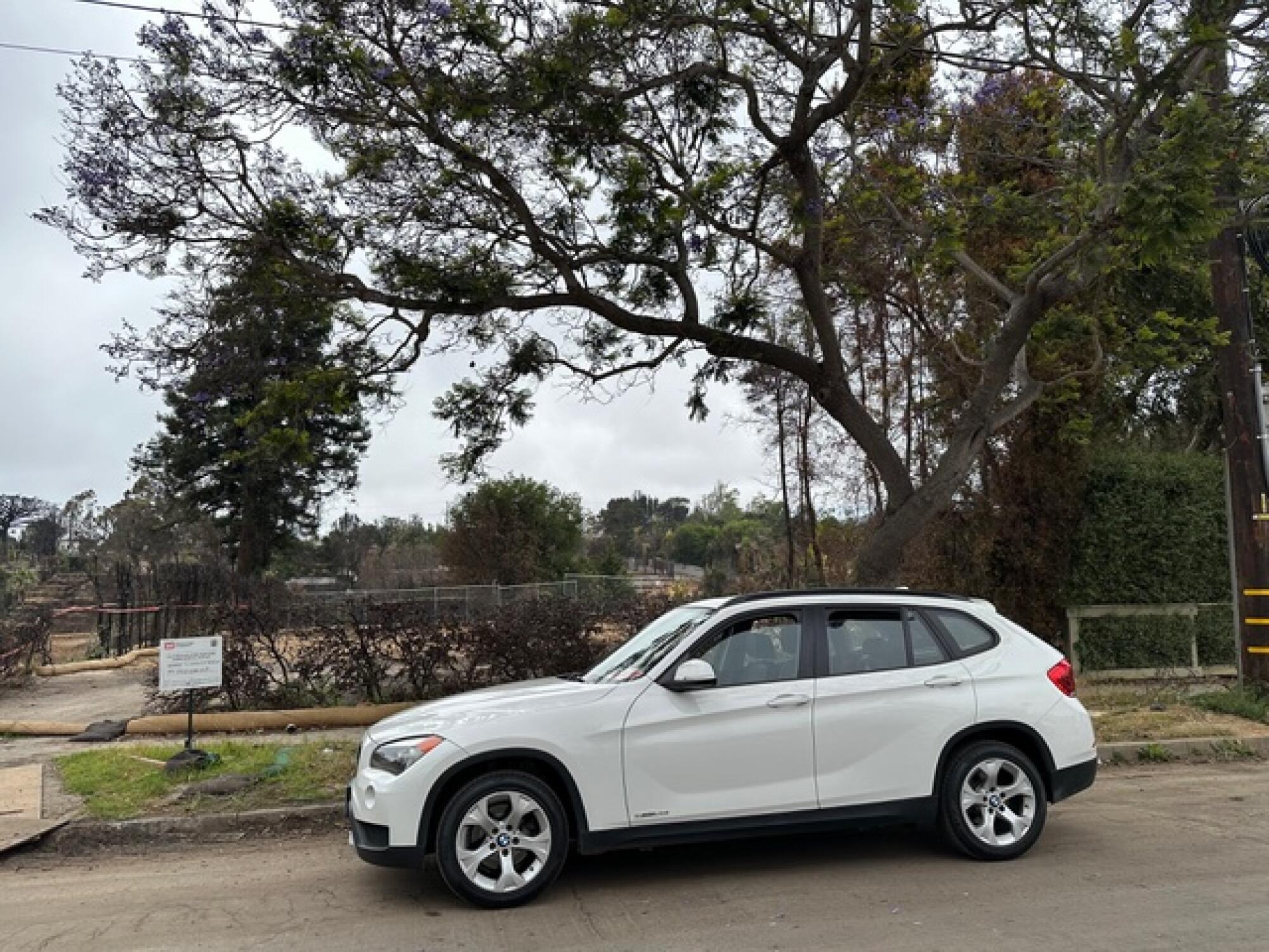 A parked white SUV with trees in the background.