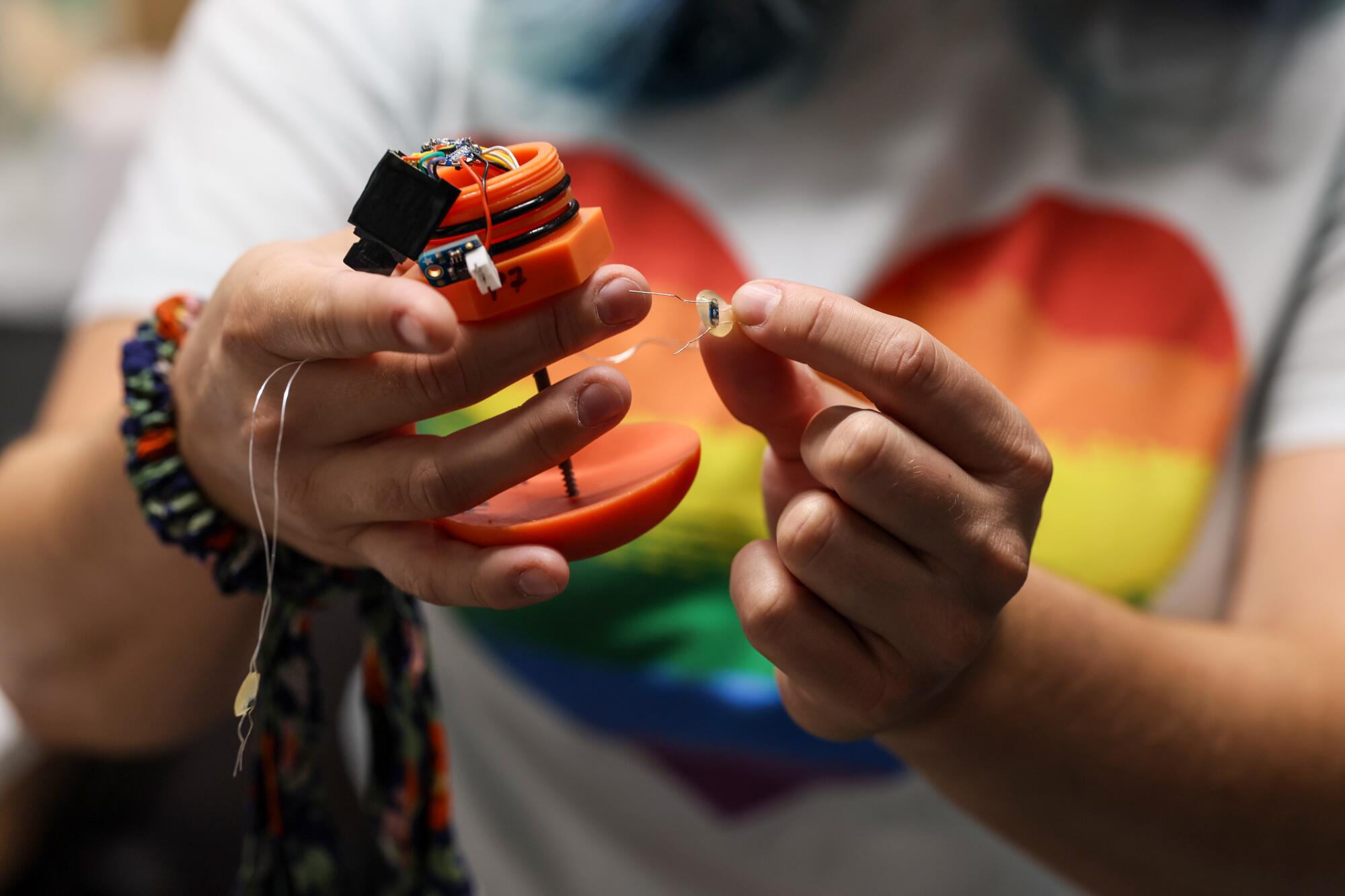 A grad student holds the device used to equip a cyborg jellyfish.