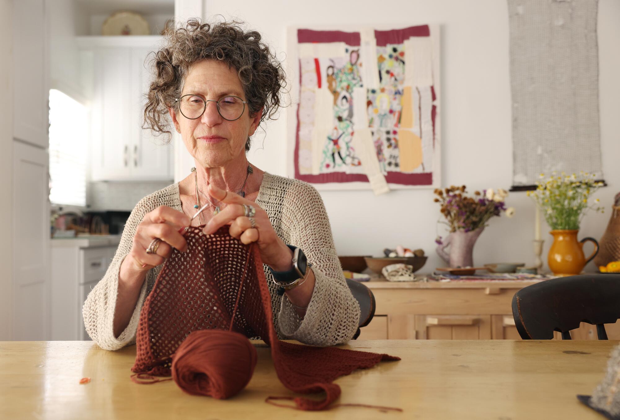 Artist Debra Weiss knits a sweater at her dining room table