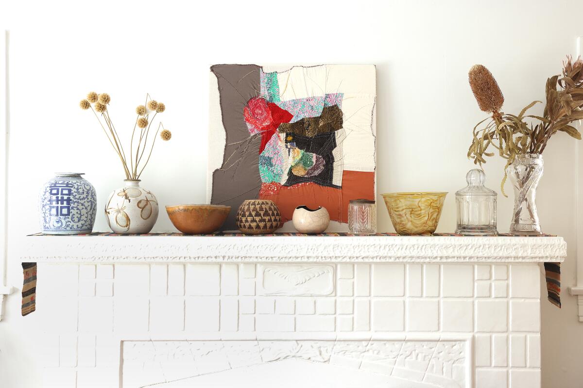 Ceramics, flowers and art rest on an all white mantle