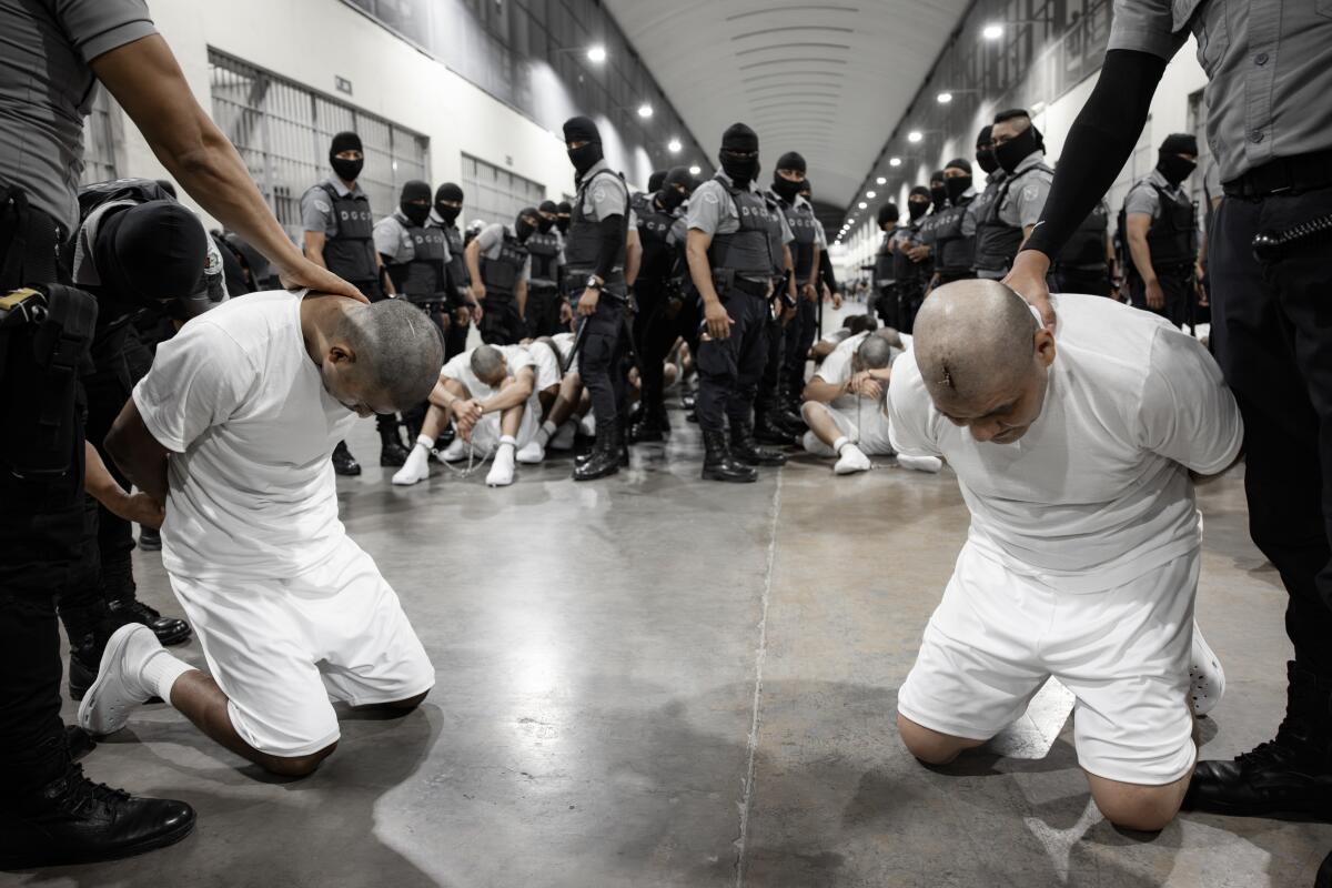 Inmates kneel on the ground at CECOT.