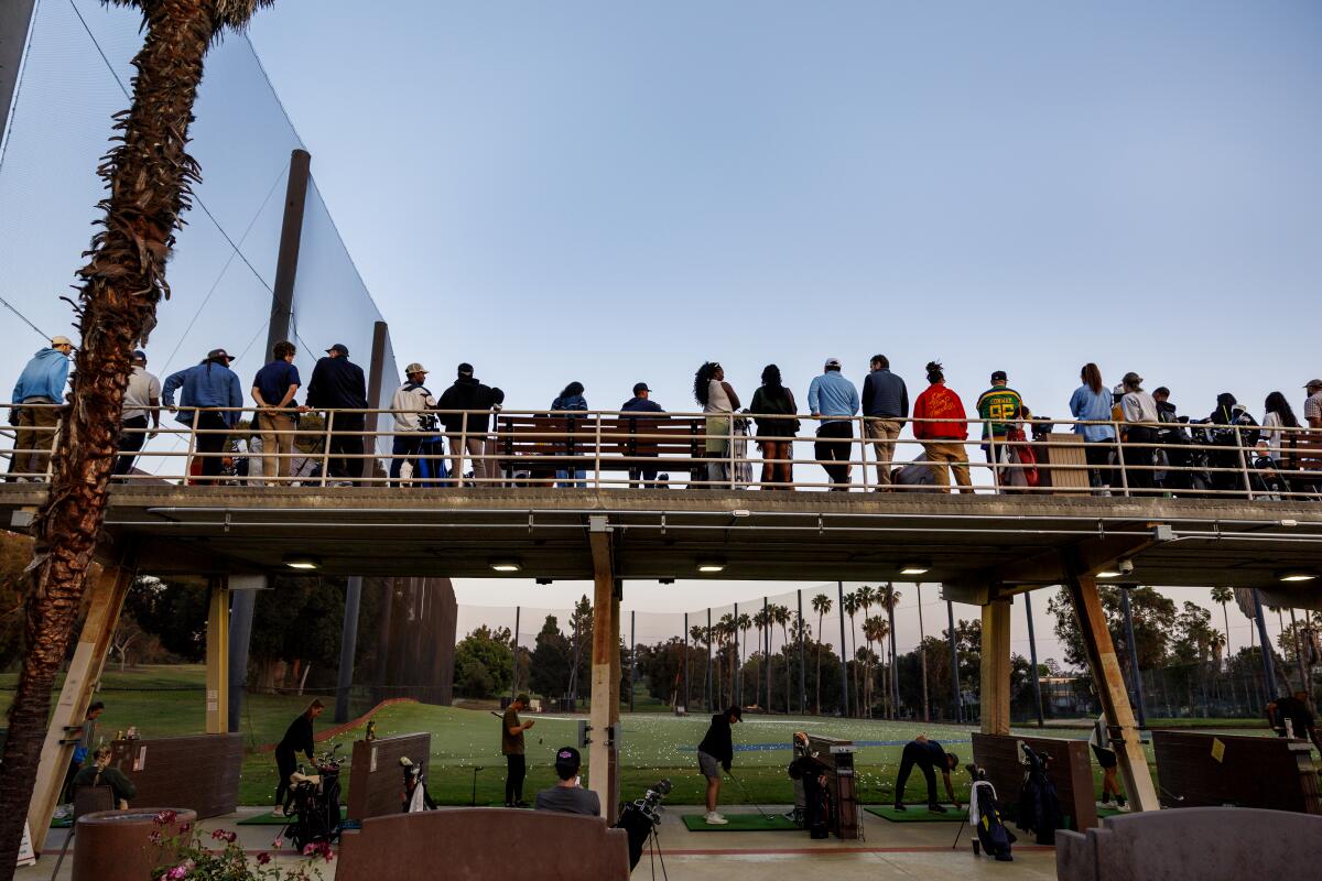 A crowd fills the top level of the driving range during a Swang golf event.