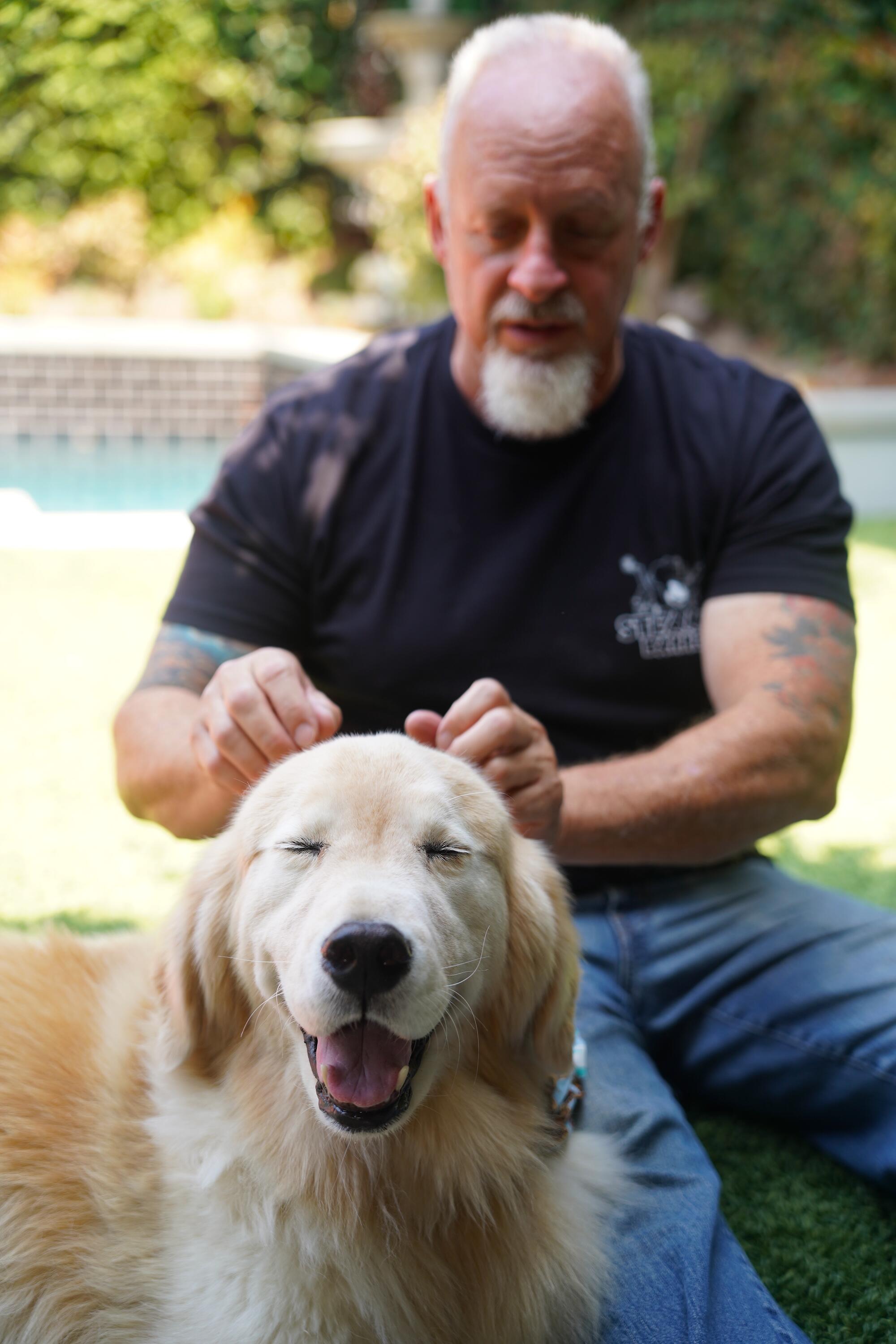  A man massages a dog's head.