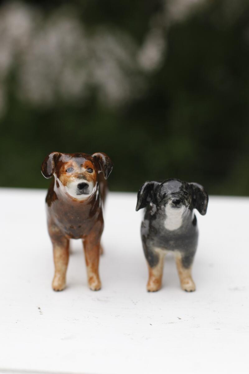 Two dog figurines stand side by side 