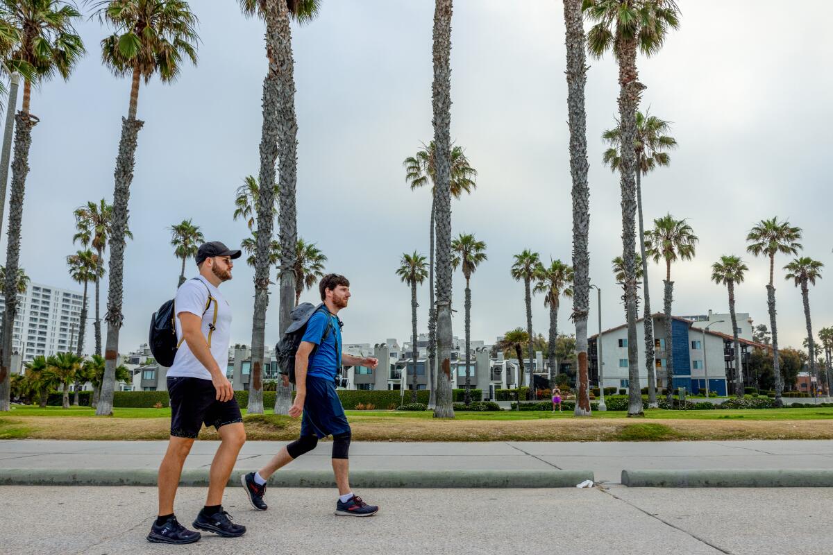 One man in a white shirt and another in a blue one on their 41-miles of walking across Los Angeles.