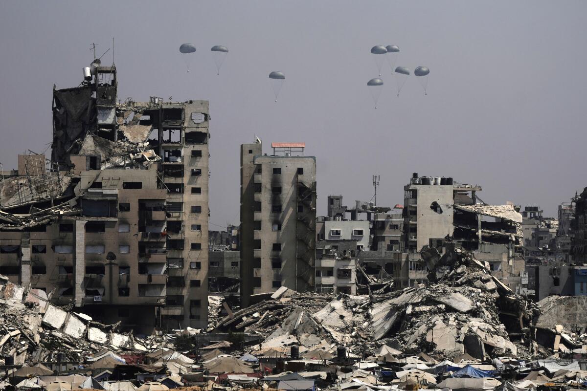 Parachutes over a ruined city landscape.