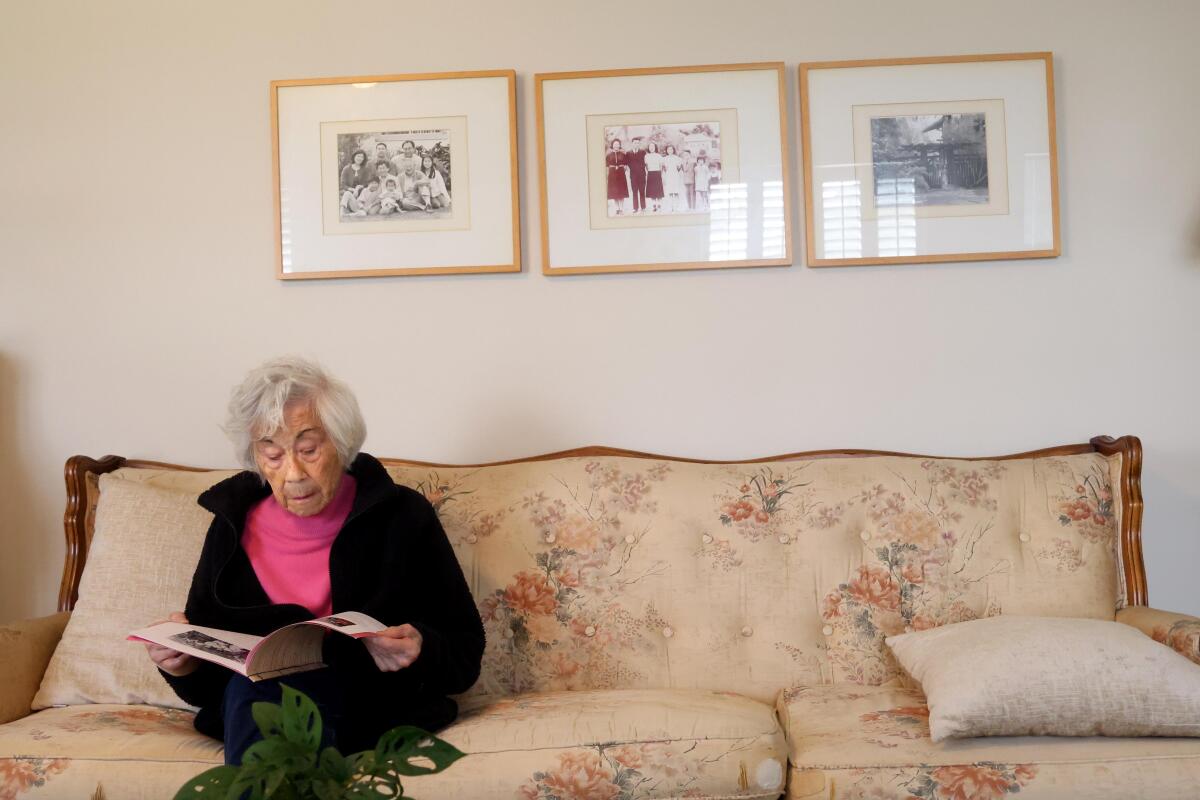 Reiko Kobata looks over a photo booklet that her family made for her 100th birthday in home in Gardena.