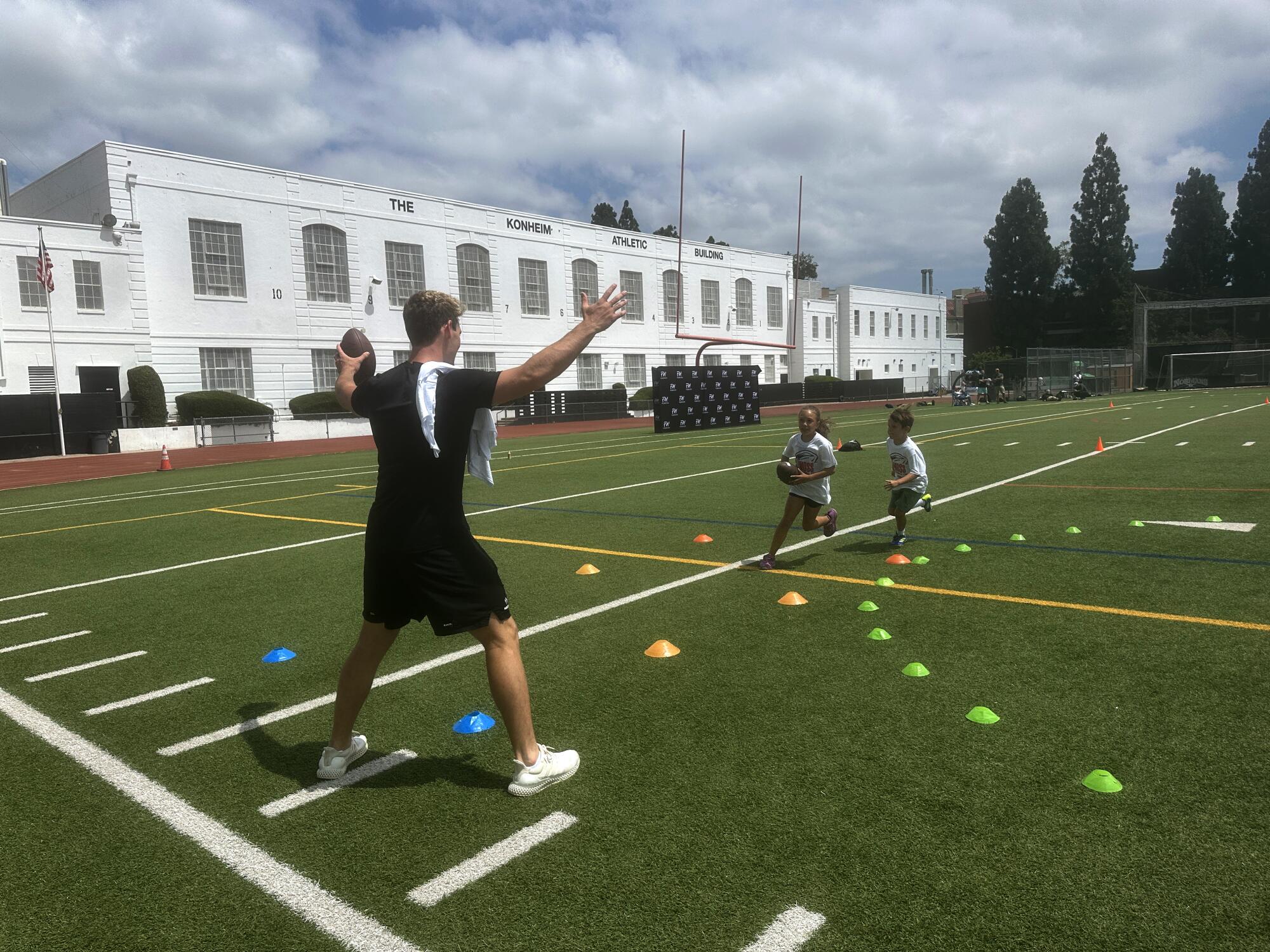 Louisville quarterback Miller Moss instructs a couple of players at his youth football camp at Beverly Hills High School.
