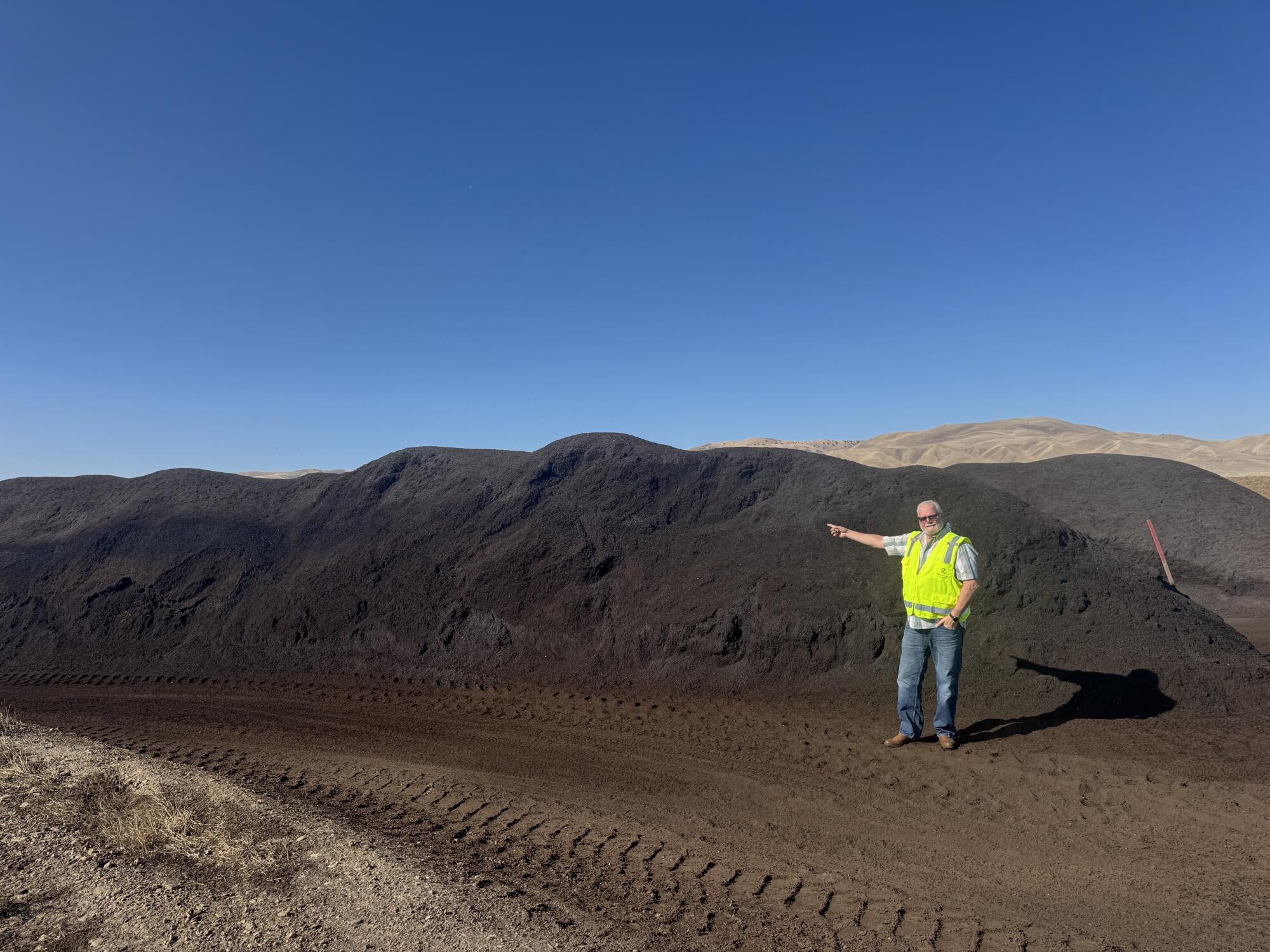 Greg Pryor, Recology's director of landfill and organics, stands in front of a pile of processed compost.