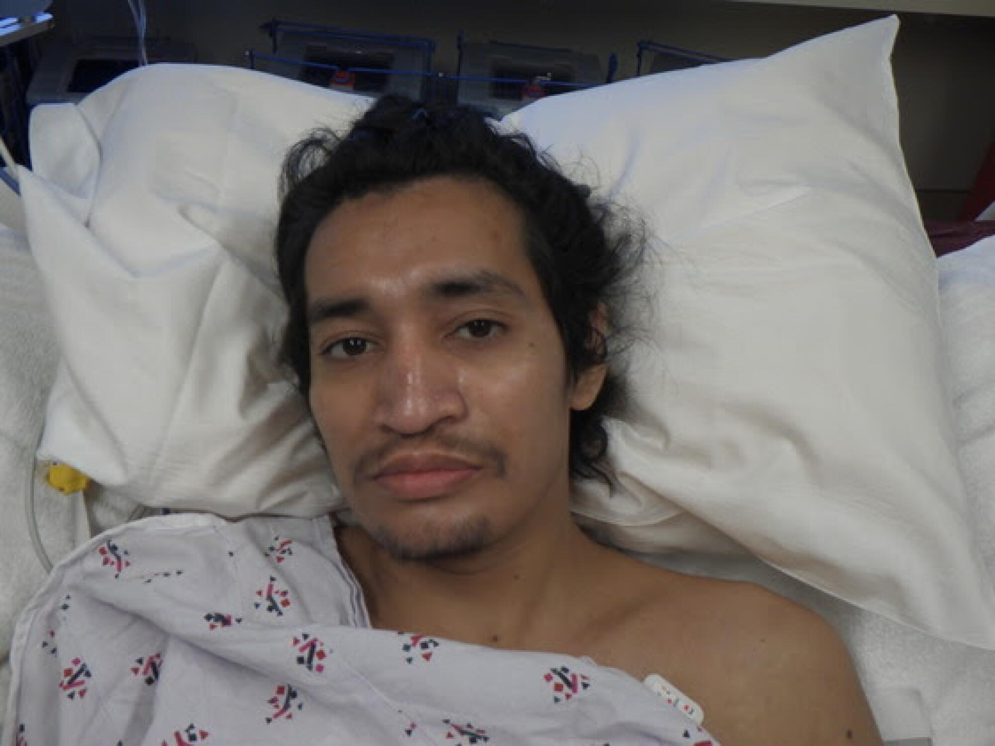 A man looks into the camera while laying in a hospital bed.