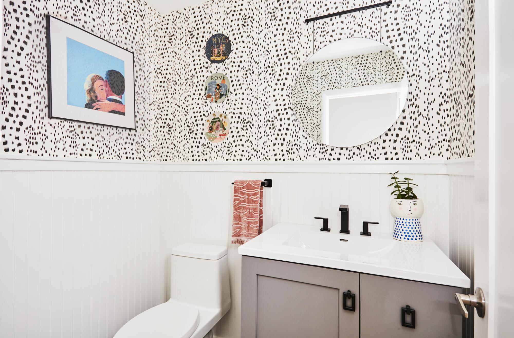Rifle Paper Co. dessert plates add contrast to the black and white wallpaper in this bathroom designed by Sarah Storms.