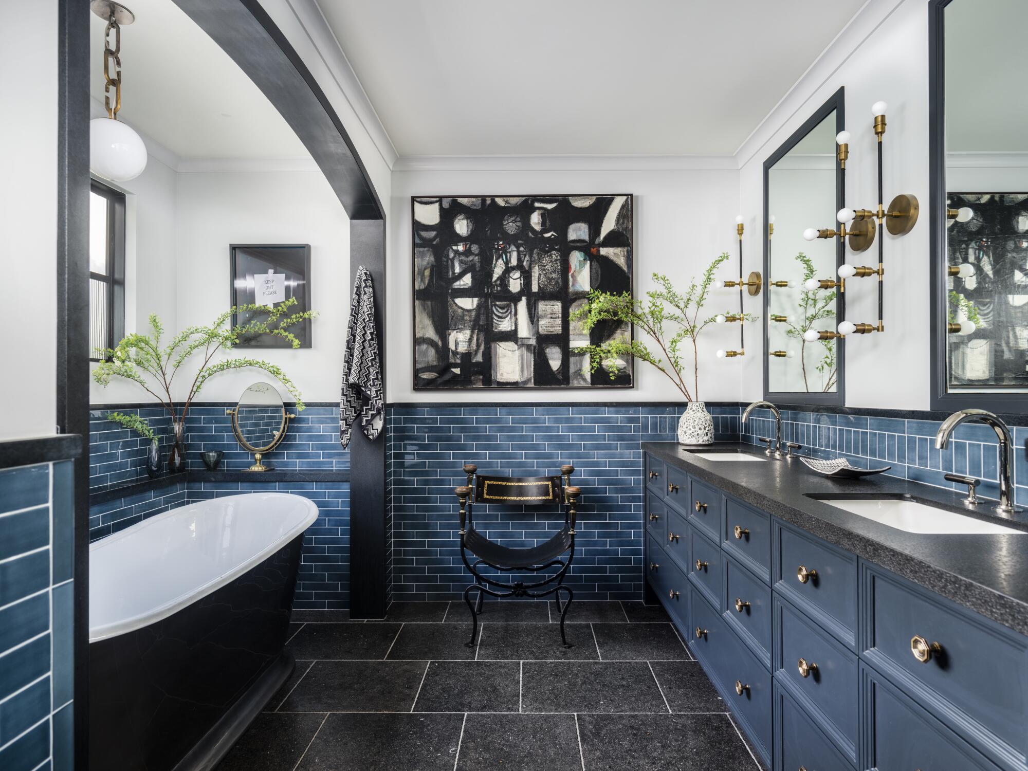 A large, bold painting pulls in the black of the tub in this Jeff Andrews-designed bathroom.