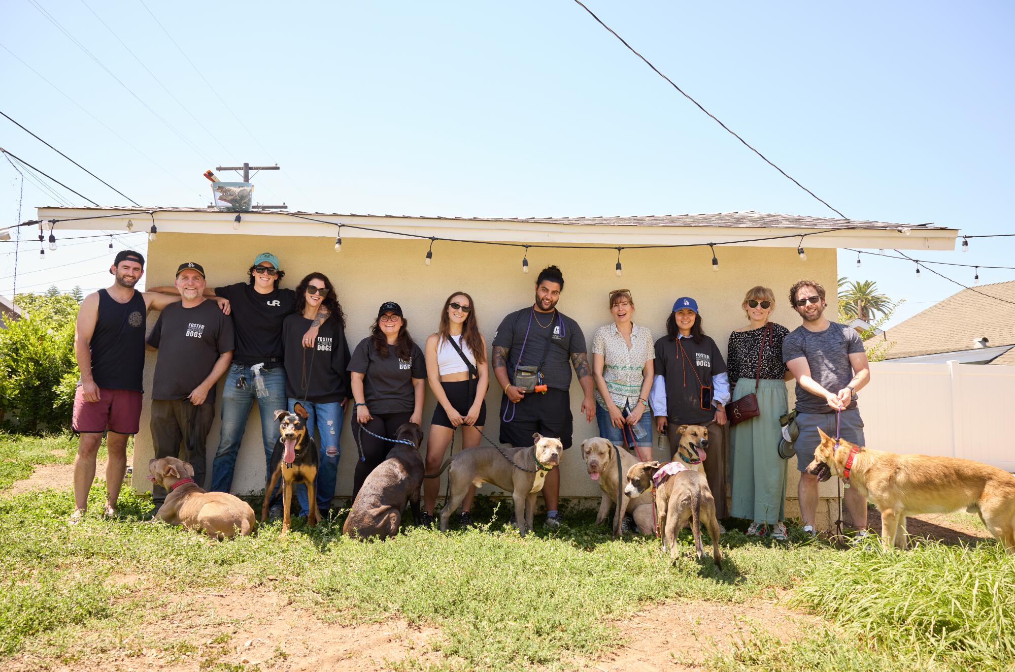 A group of people and dogs post in front of a house. 