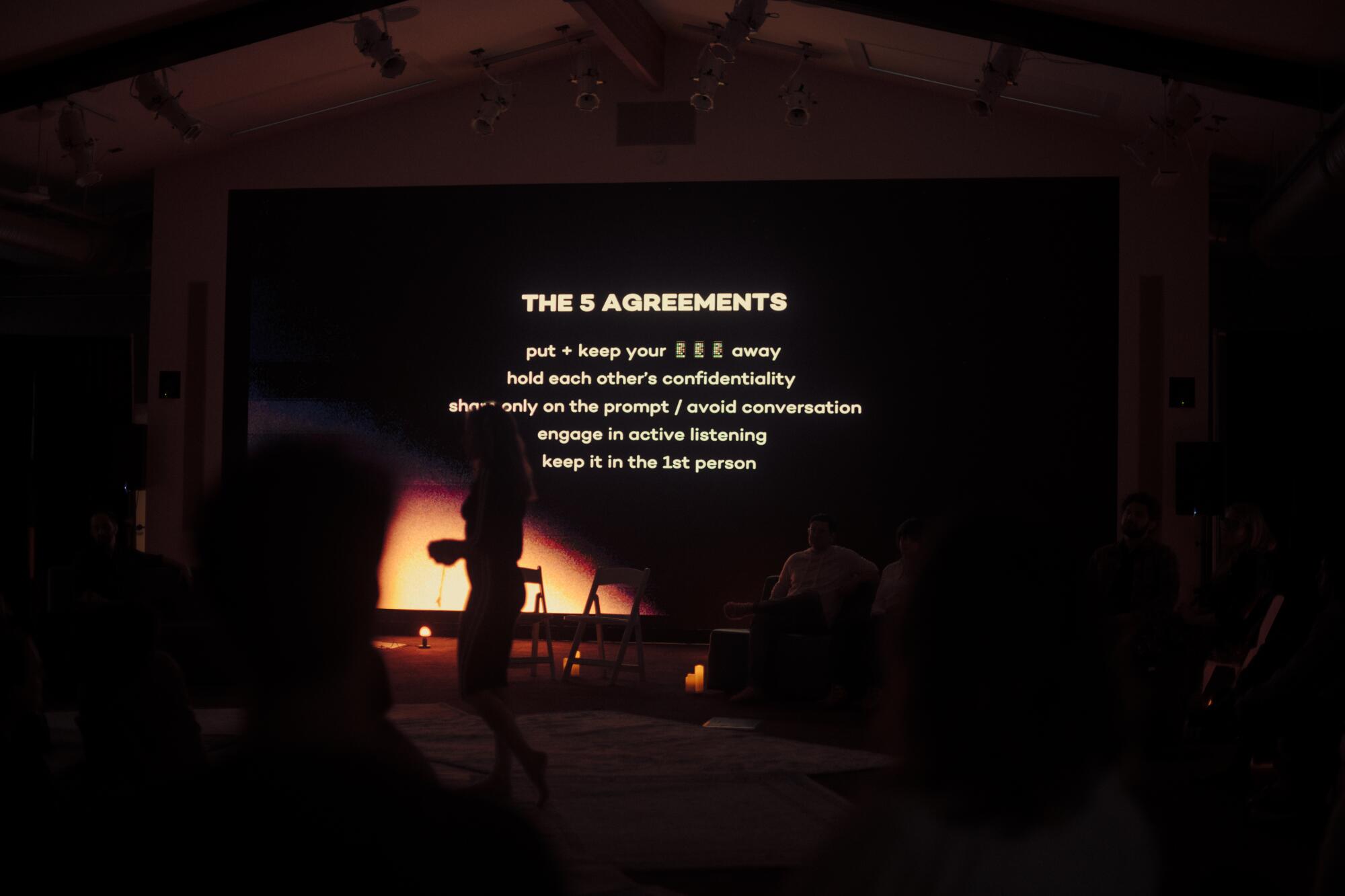 Text is shown on a giant screen in a dark room