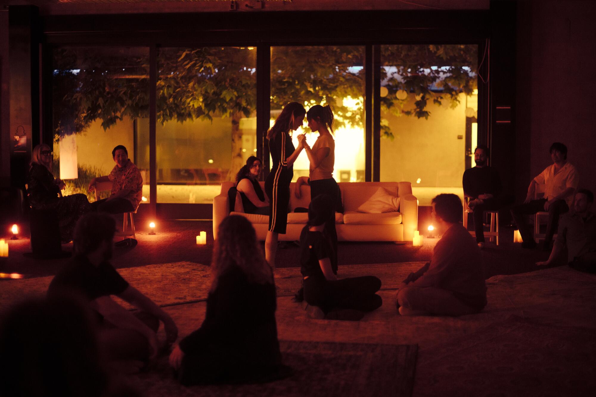 Participants sit on the ground or stand, facing one another. 