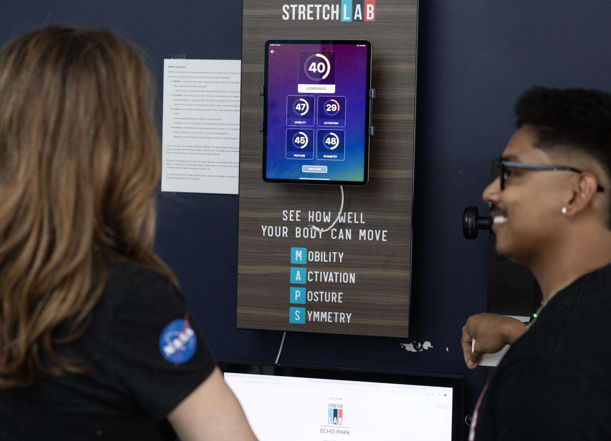 A man and woman shown from behind looking at assessment scores on an iPad.