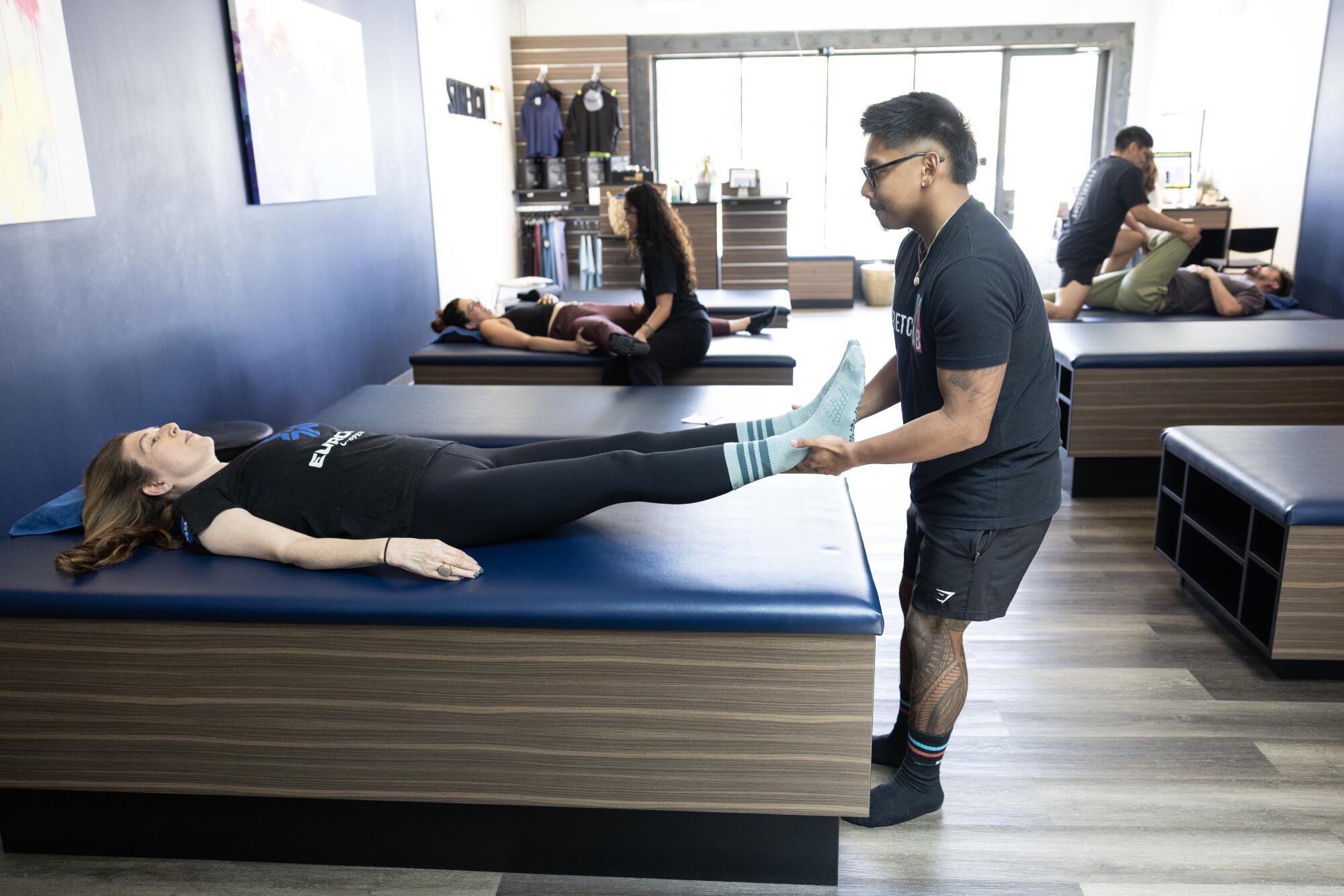 A woman lays on a massage table as a man tugs on her legs. 