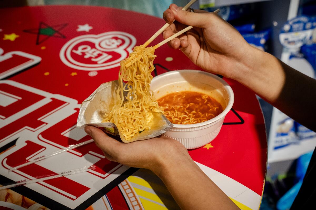 A detail of a person cooling down noodles in a DIY cone made from the ramyon bowl cover.
