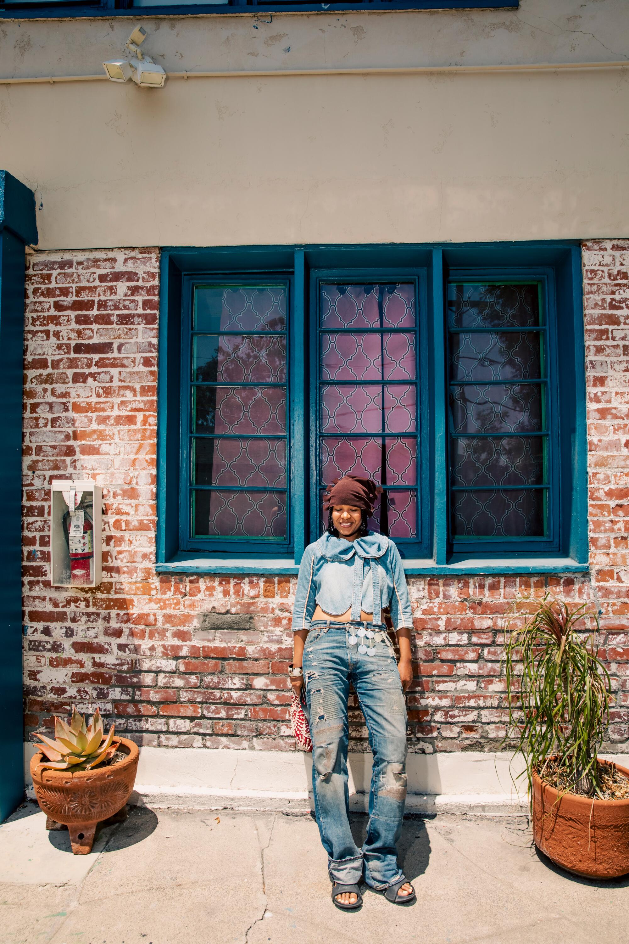 Kaamilah Thomas wears hat, jacket, Levi’s, shoes, Gianfranco Ferré purse, belt, and pendant.