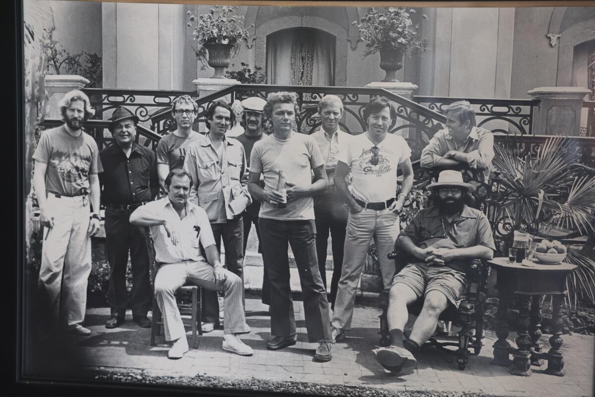 A black and white photo of 11 men dressed in 1960s clothes.