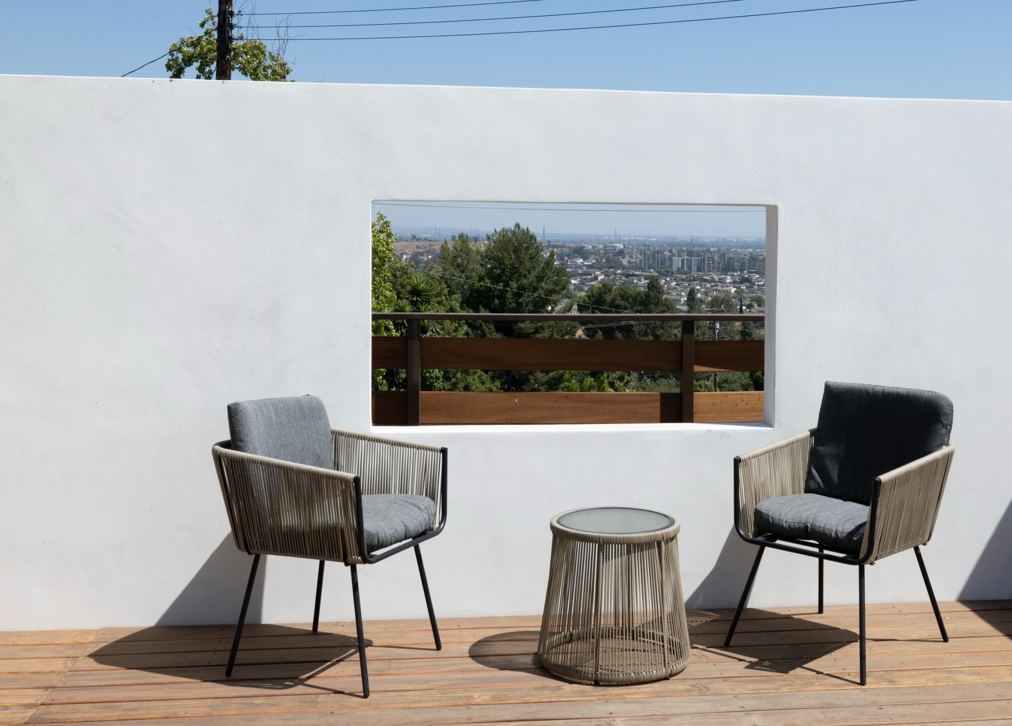 Two chairs rest in front of a partial height wall with a window.