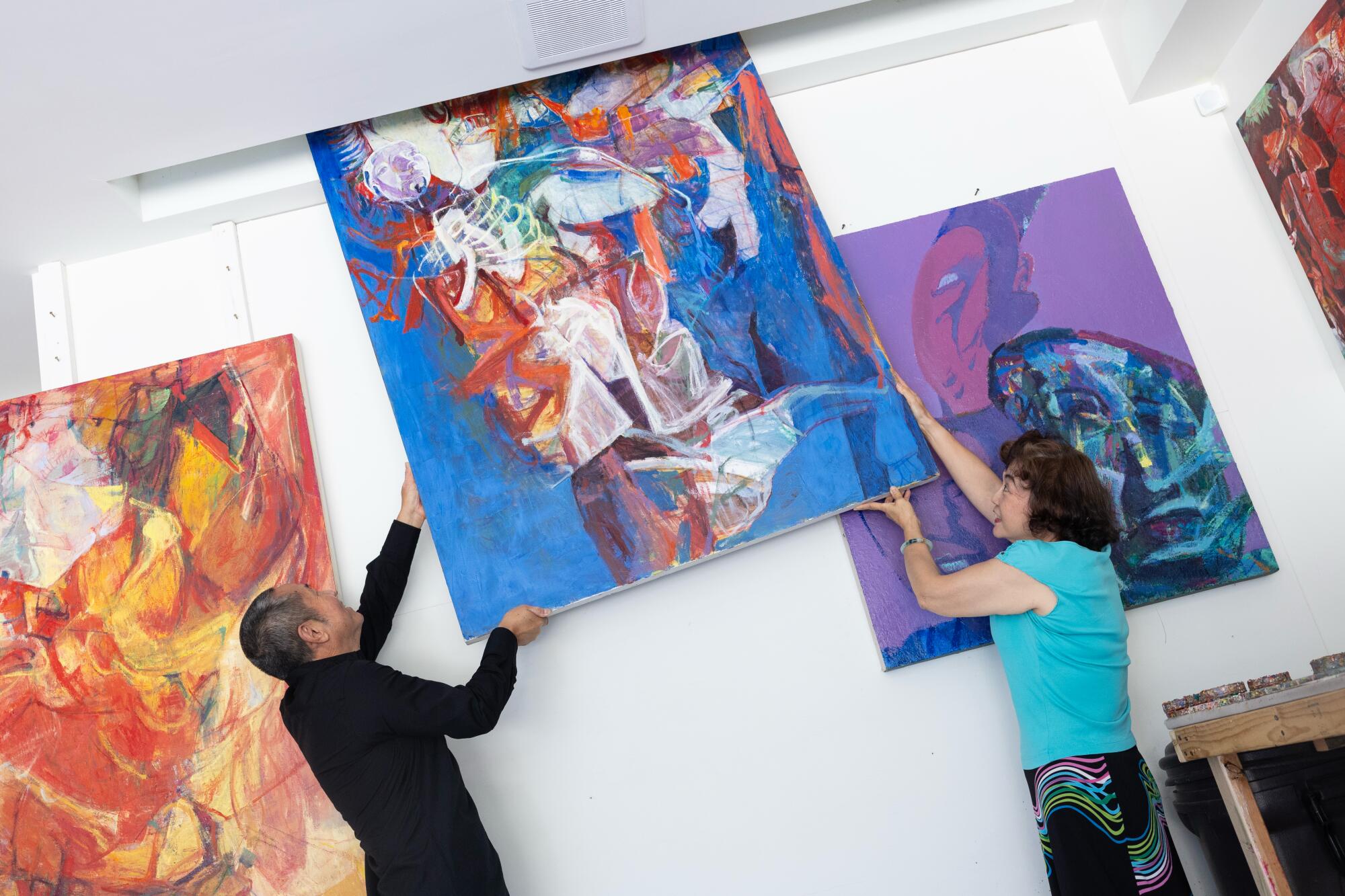 A couple move a large oil painting through a hole in the ceiling
