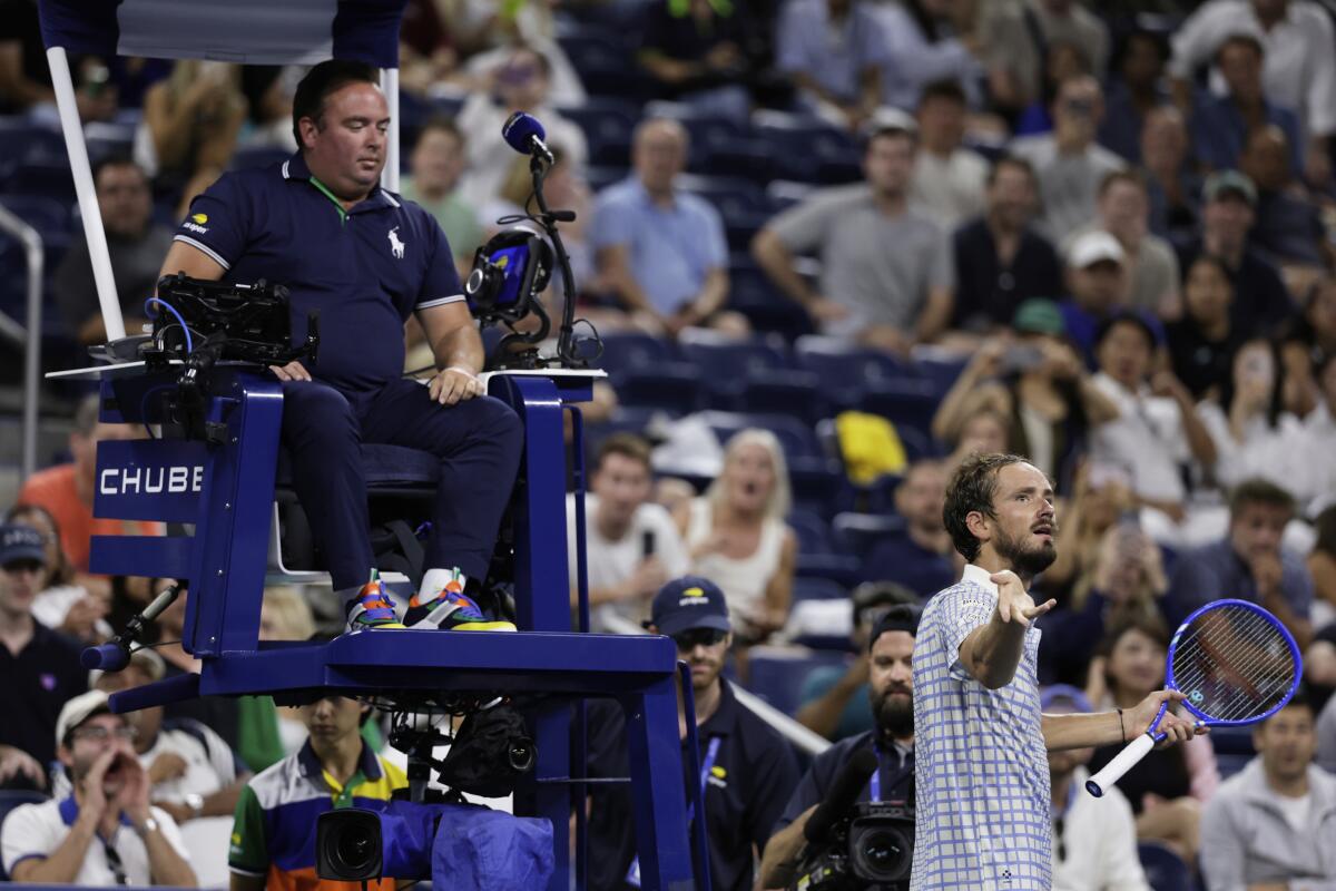 Daniil Medvedev holds his arm and racket up beside chair umpire Greg Allensworth