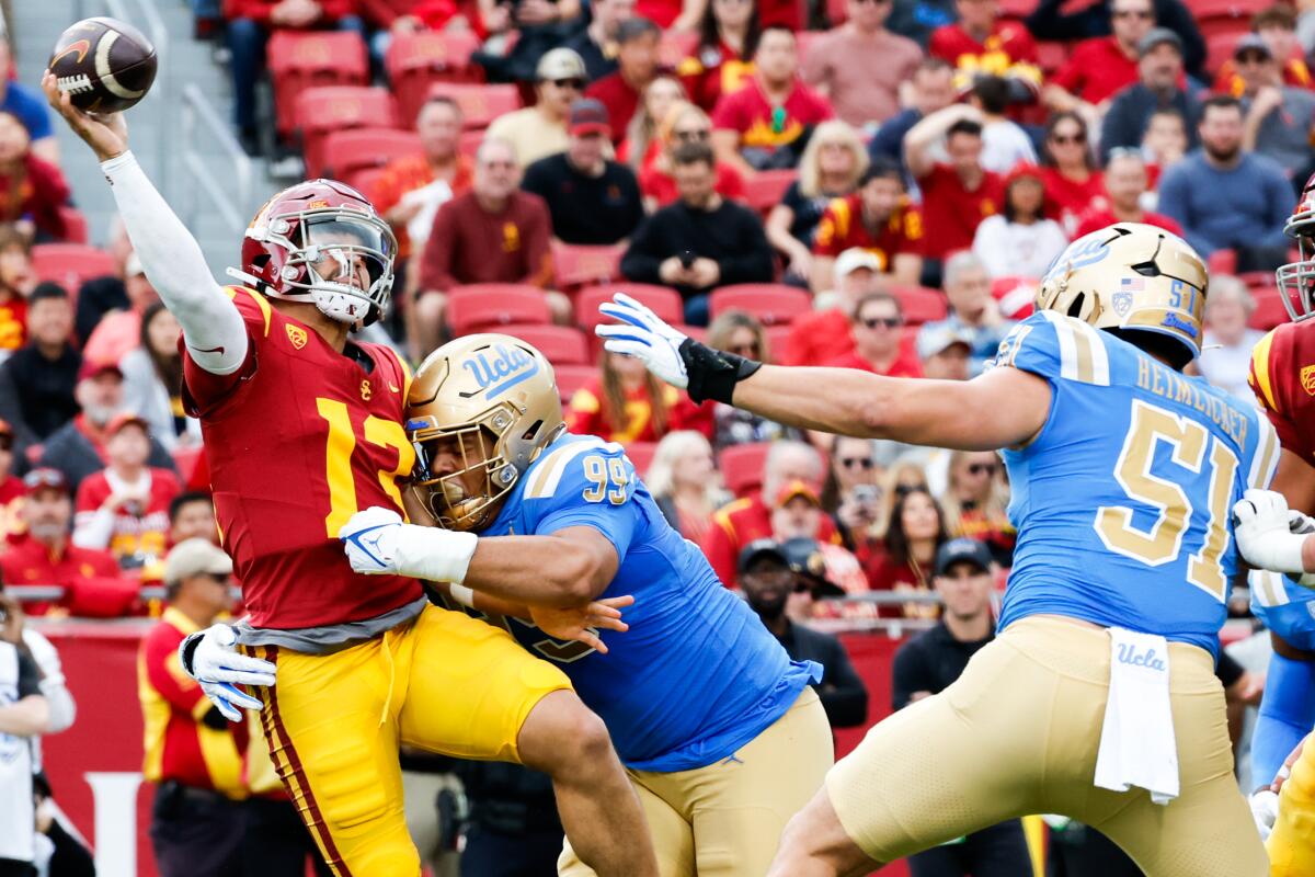 UCLA defensive lineman Keanu Williams hits USC quarterback Caleb Williams as he throws the ball.
