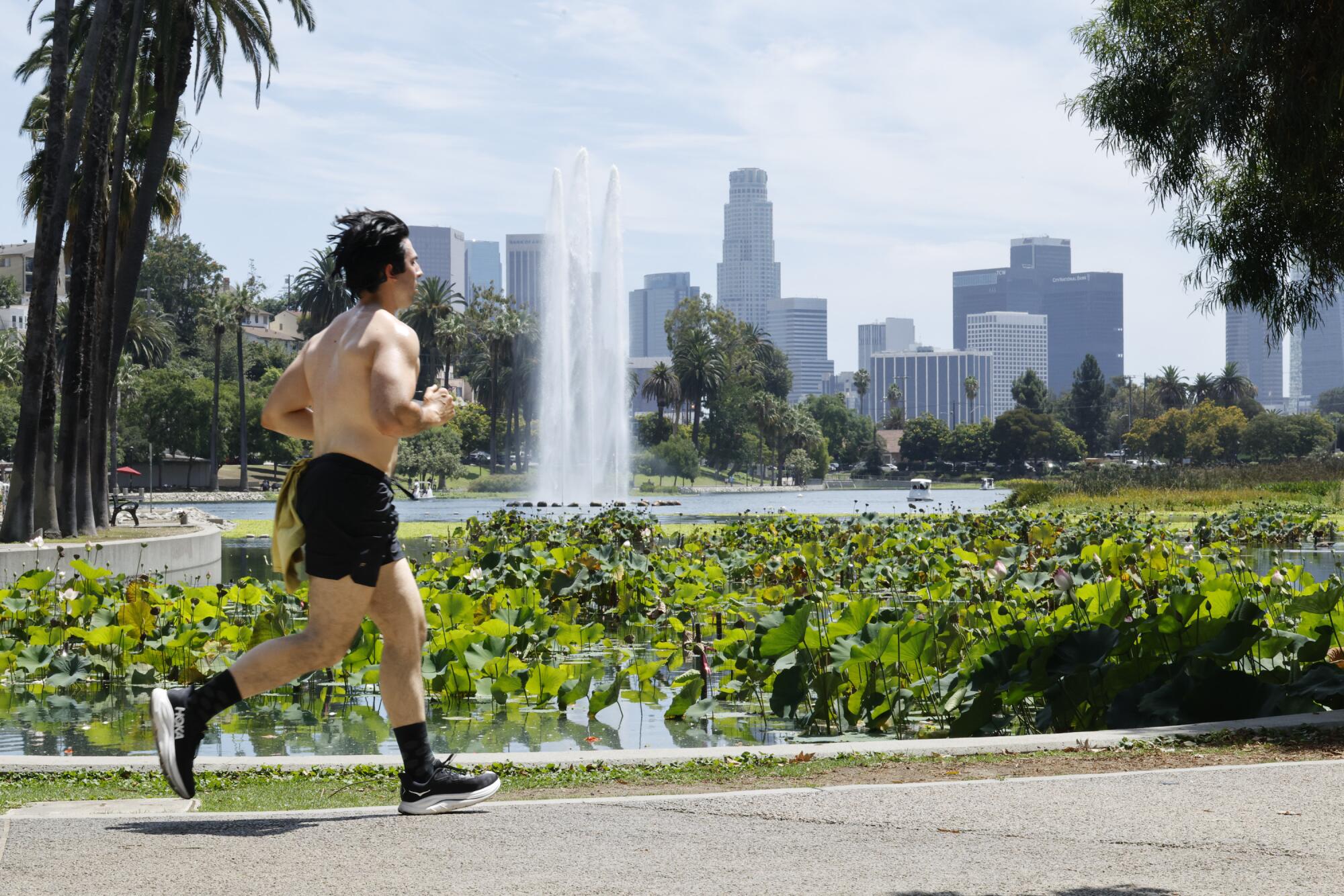 A runner passes by the downtown skyline at Echo Park Lake amid a heat wave on Thursday in Los Angeles.