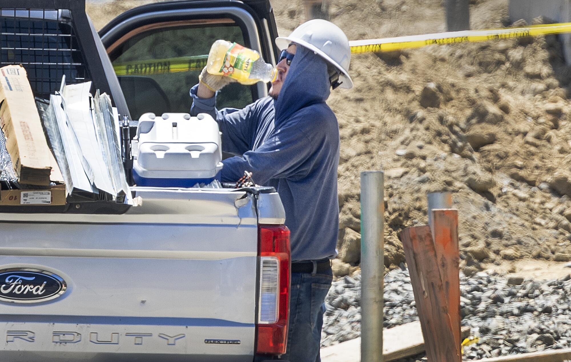 A construction worker takes a water break while working on new homes amid a heat wave on Wednesday in Irvine.