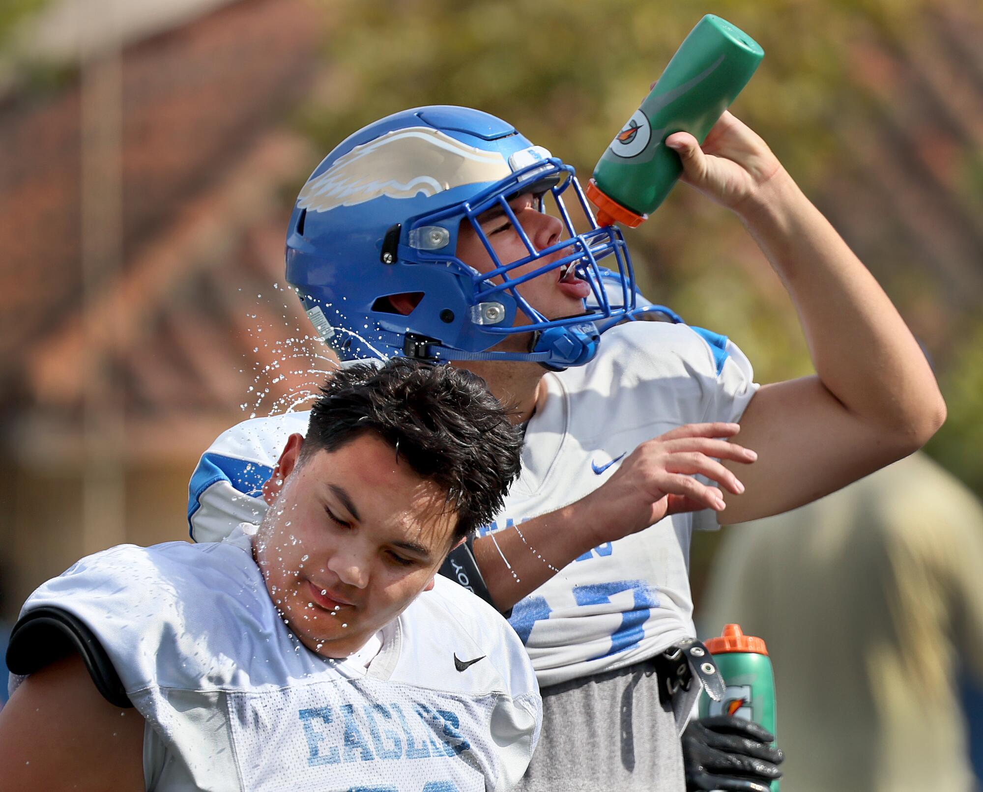 Football players take a break from practice to hydrate and cool off amid high temperatures at Santa Margarita High.