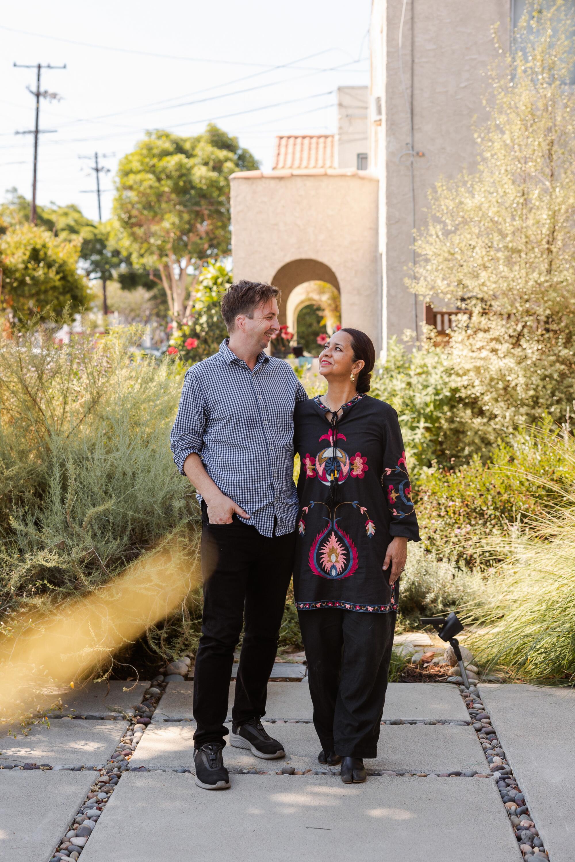 Christian Svanes Kolding, left, and his wife, Adriana Estrada, stand in their front yard.