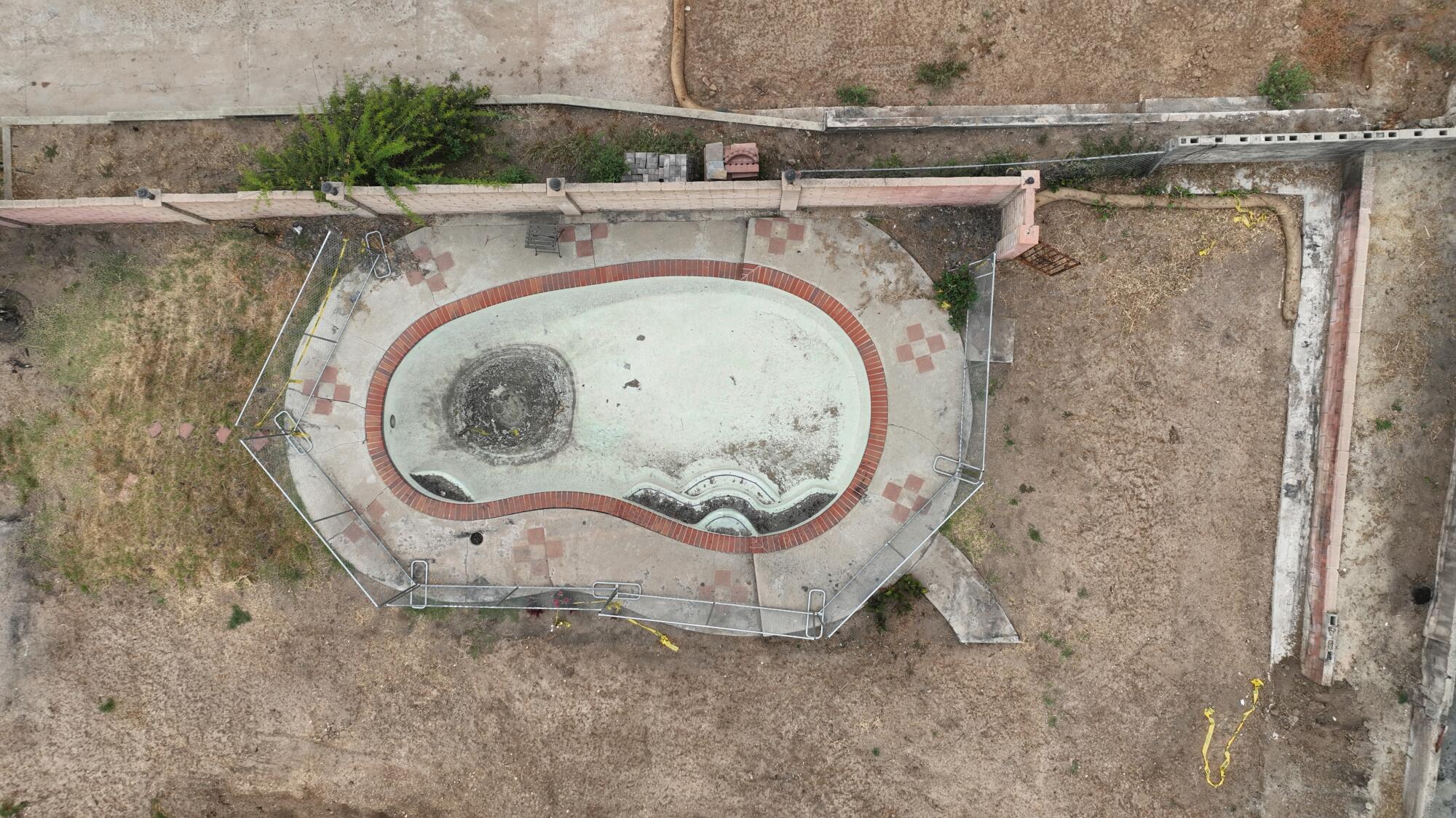 An empty swimming pool sits on a mostly cleared property 