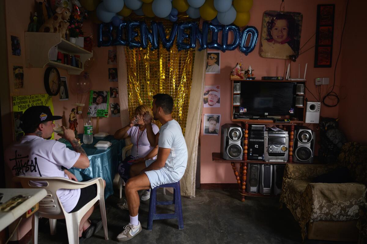 Two men and a woman seated at a table inside a home
