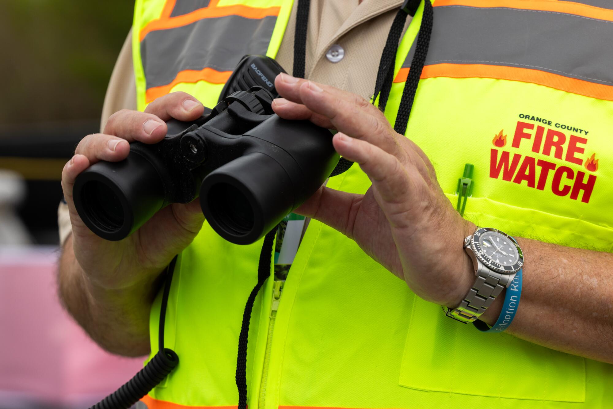 Orange County Fire Watch volunteer Phil Sallaway holds binoculars during a mock deployment for the media at Ridge Park