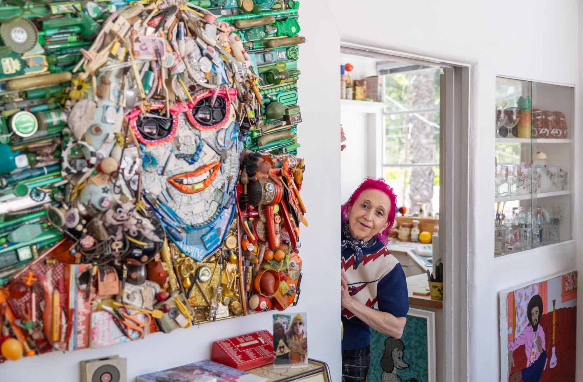 Author Hillary Carlip smiles next to art made of trash that looks like her friend Allee Willis.