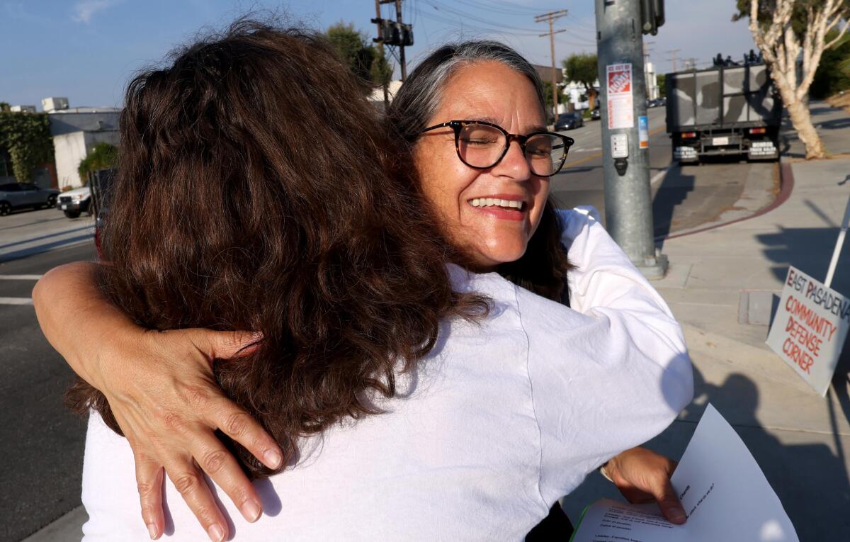 Sharon Nicholls gets a hug of support from another protester outside the Home Depot in Pasadena.