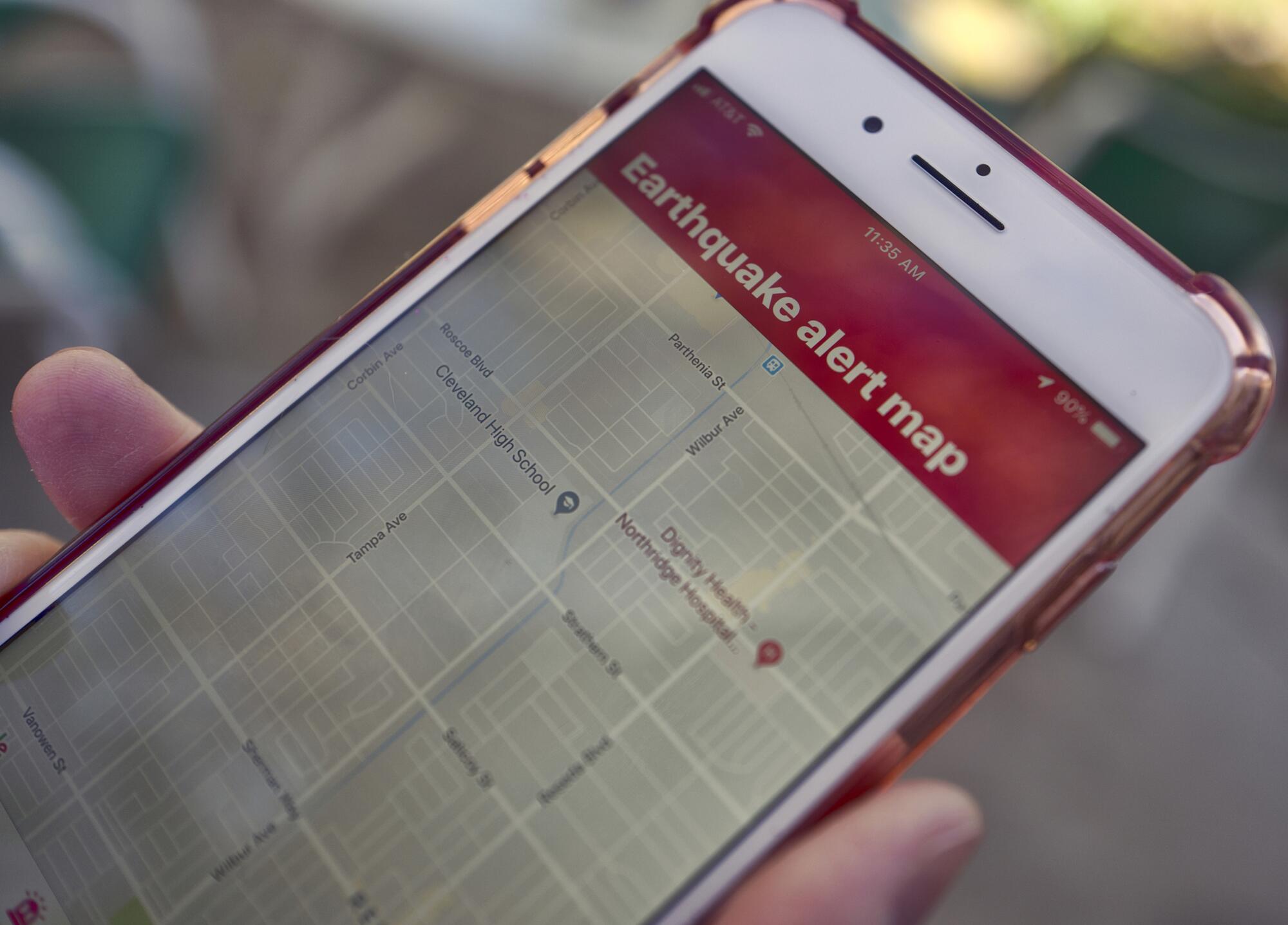a mobile phone customer looks at an earthquake warning application