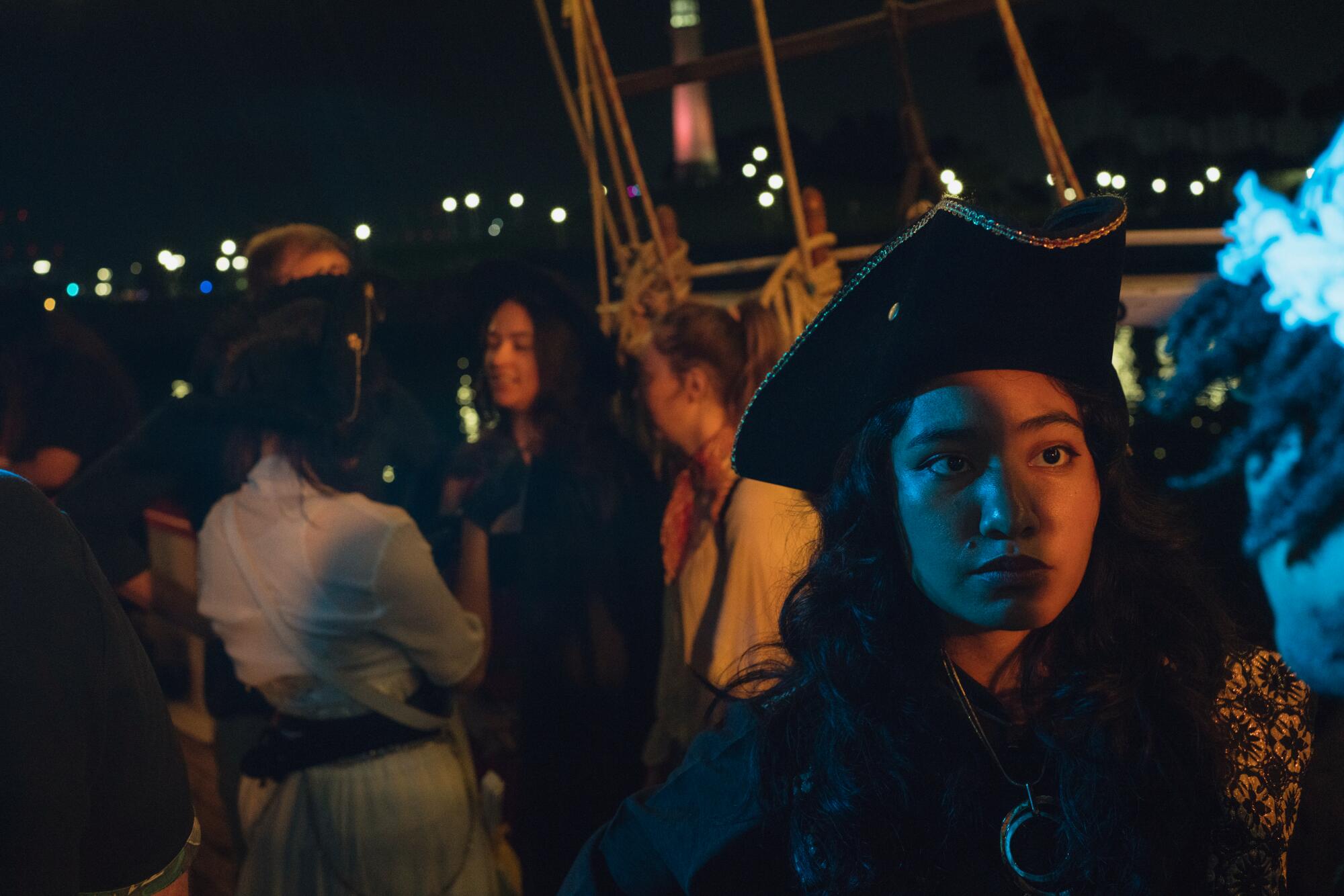 An actor in pirate gear stands in front of an audience on a ship.