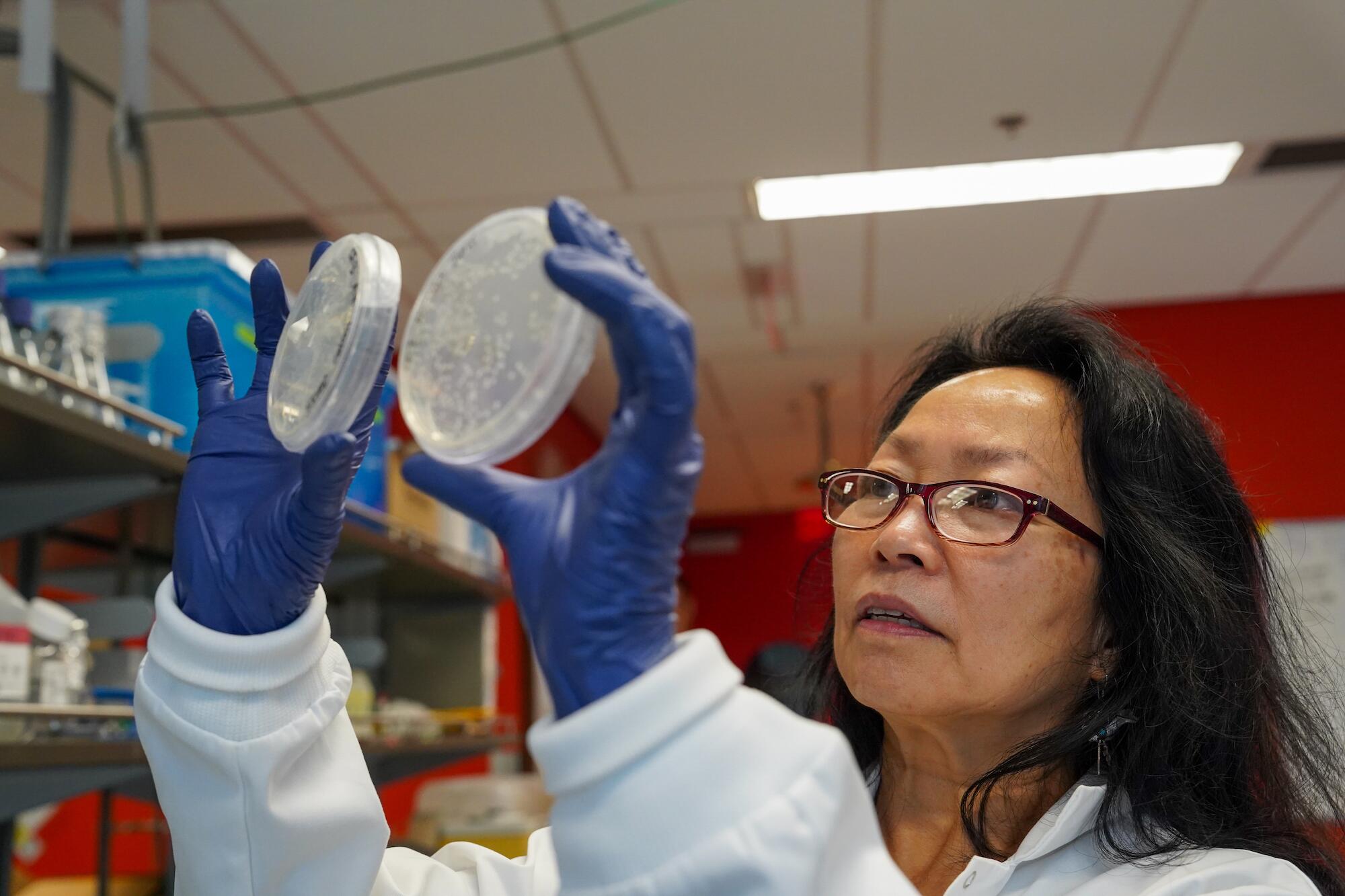 A scientist holds up two small containers.
