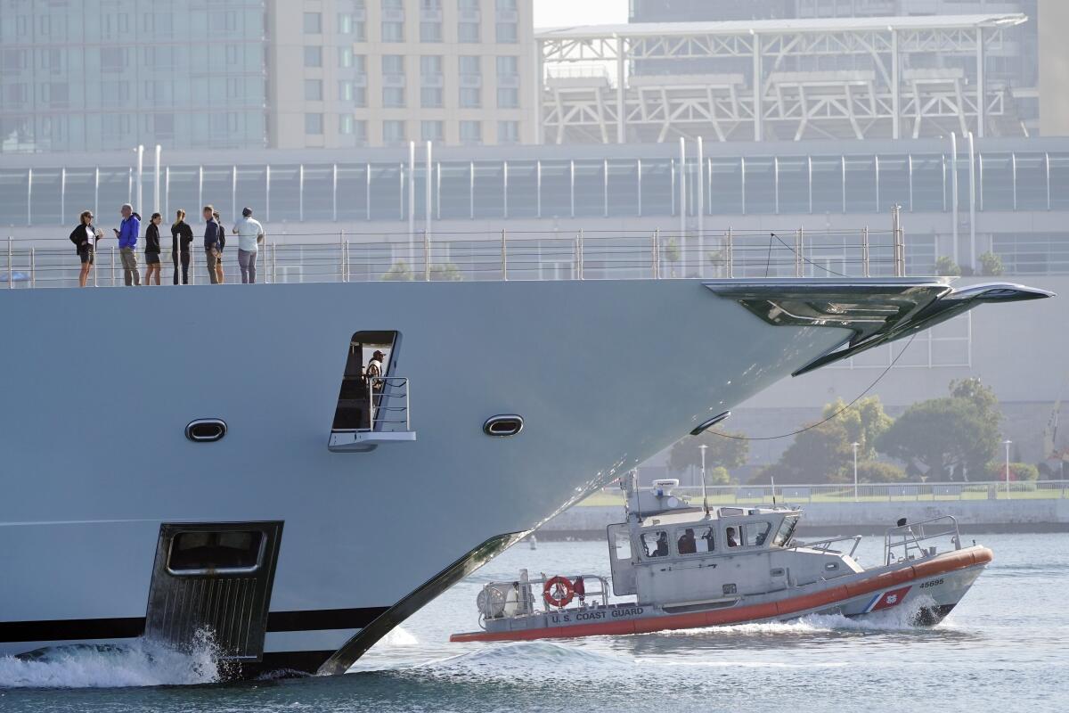 A small boat is seen beneath the bow of a large boat.