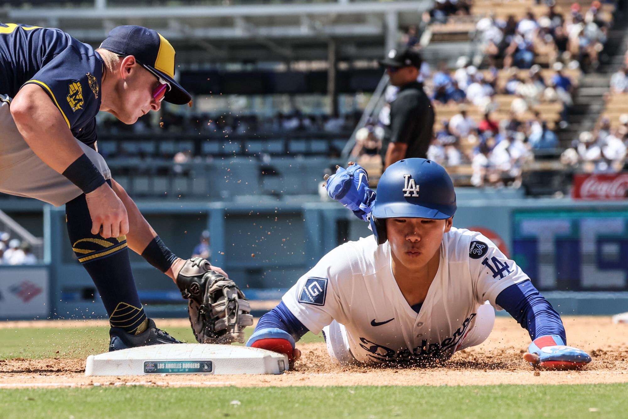 Dodgers first baseman Freddie Freeman slides safely into first past in front of Brewers first baseman Andrew Vaughn.