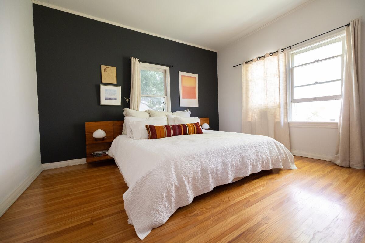 A white bed against a charcoal wall of a bedroom.