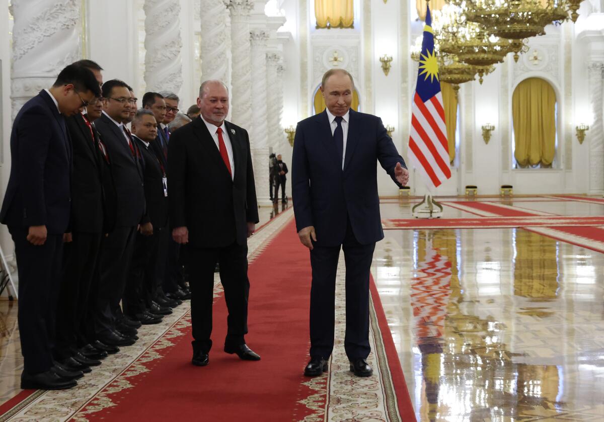 Russian President Vladimir Putin and King of Malaysia Sultan Ibrahim walk during a welcoming ceremony at the Kremlin