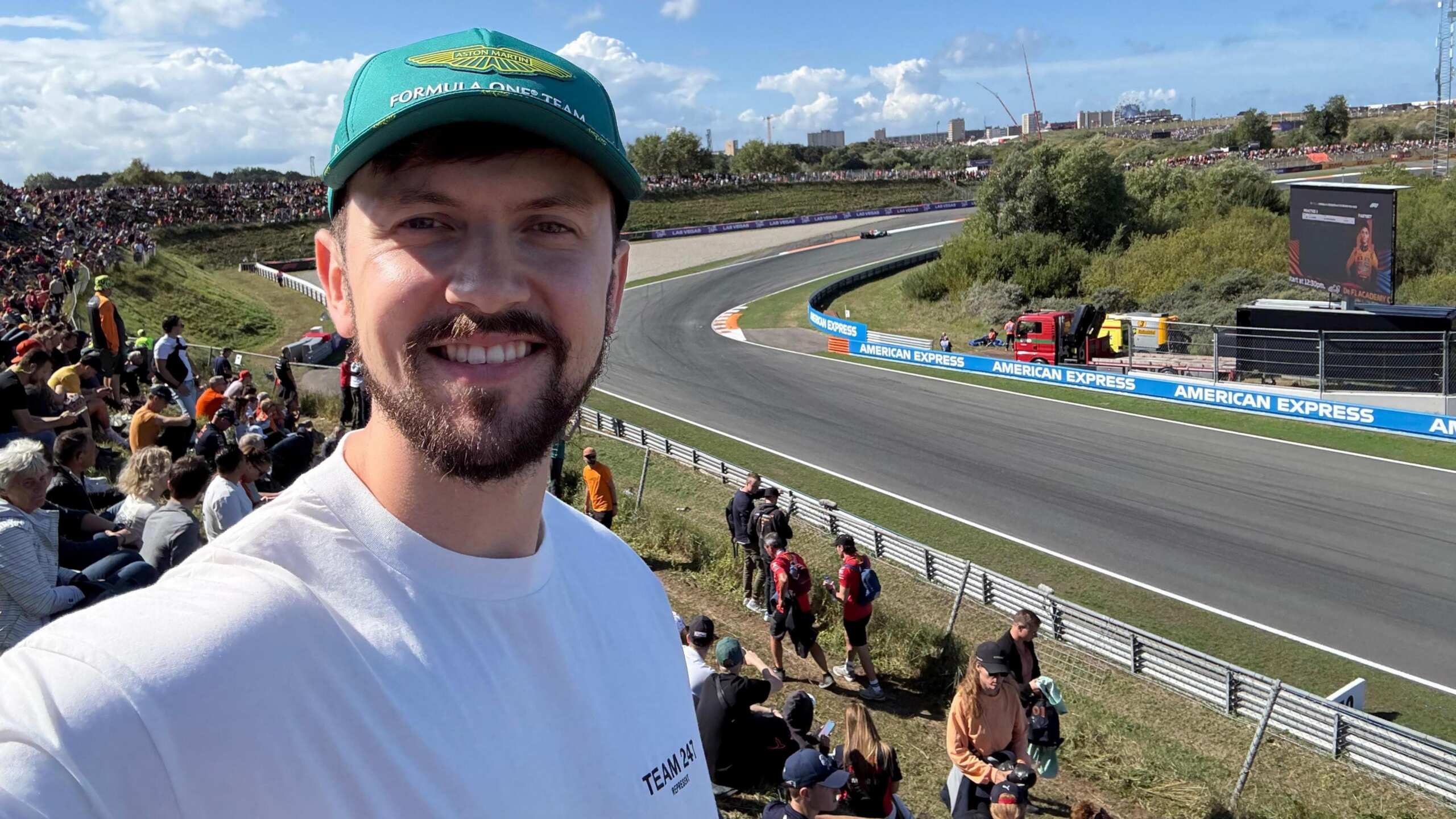 Brandon Burgess smiles while taking a selfie with the Zandvoort circuit in the background