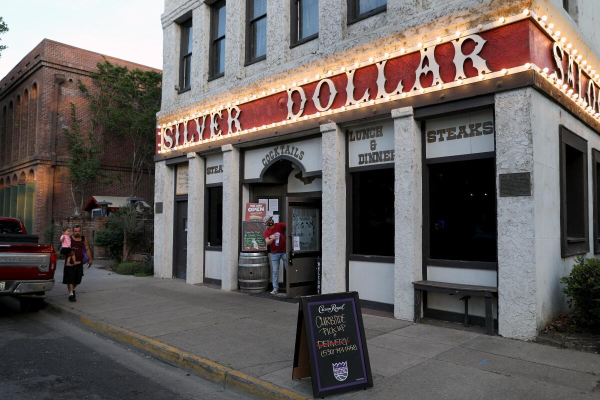 The exterior of a two-story, modest white brick building with a sign that says Silver Dollar.