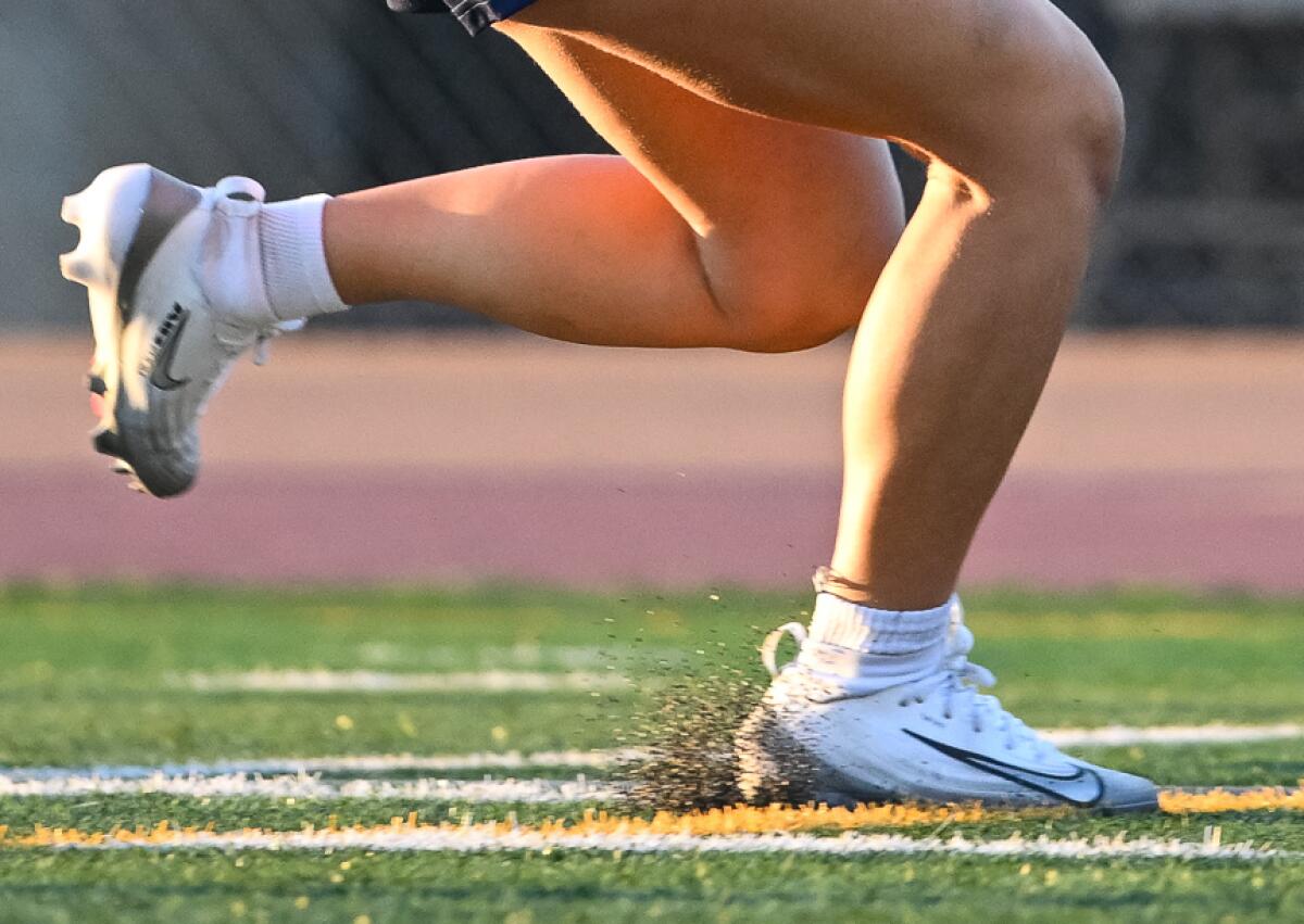 A flag football kicks up pellets on the artificial turf at Oxnard High School.