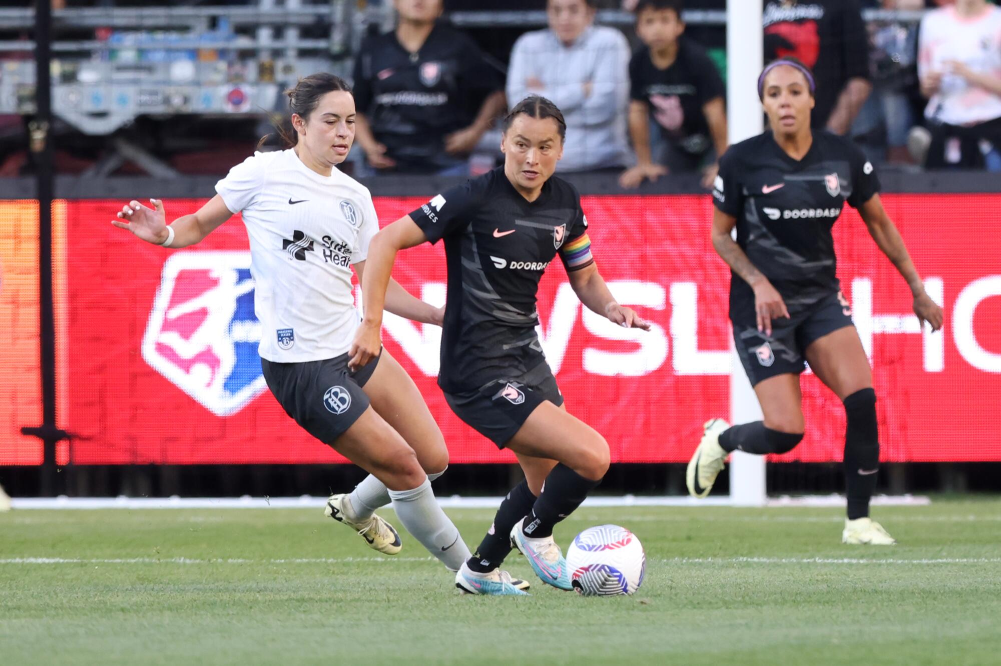Angel City captain Ali Riley dribbles the ball under pressure from Bay FC's Scarlett Camberos during a 2024 game.