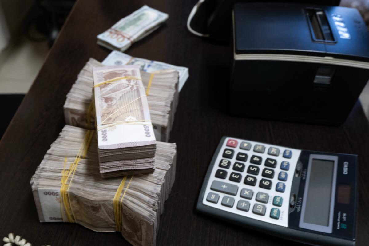 A stack of money sits on a desk in a bank.